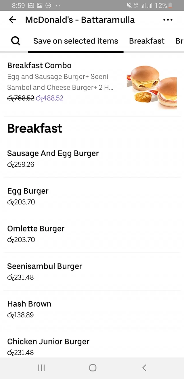 The image is a screenshot of a menu from McDonald's in Battaramulla, featuring breakfast items. The top section advertises a "Breakfast Combo" with items like an Egg and Sausage Burger, Seeni Sambol, Cheese Burger, and more, originally priced at LKR 768.52 but discounted to LKR 488.52. Below this, a list of individual breakfast items is displayed with their respective prices. The items include a Sausage And Egg Burger for LKR 259.26, an Egg Burger and Omlette Burger both for LKR 203.70, a Seenisambul Burger and Chicken Junior Burger each priced at LKR 231.48, and a Hash Brown for LKR 138.89. The menu is plain with a simple black font on a white background, making the items and prices easy to read. The screenshot appears to be taken from a mobile device, as indicated by the visible status bar at the top showing the time, battery percentage, and network status. The layout is clean and minimalistic, focusing on the food items and their affordability.