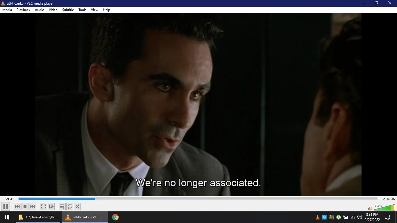 A scene from a video is displayed in VLC media player on a Windows computer. The screen shows a close-up of a man in a suit and tie, leaning slightly forward, engaged in a serious conversation. His expression is intense and focused as he speaks. The lighting is dim, suggesting a tense or dramatic moment. Subtitles at the bottom of the screen read, "We're no longer associated." The VLC media player interface is visible, showing the video file name, "utl-tlc.mkv," and the time stamp of 29:40 out of a total duration of 1:48:46. The Windows taskbar at the bottom shows various icons, including the VLC icon, indicating that it is the active application. The date and time displayed are 8:31 PM on 2/27/2022.