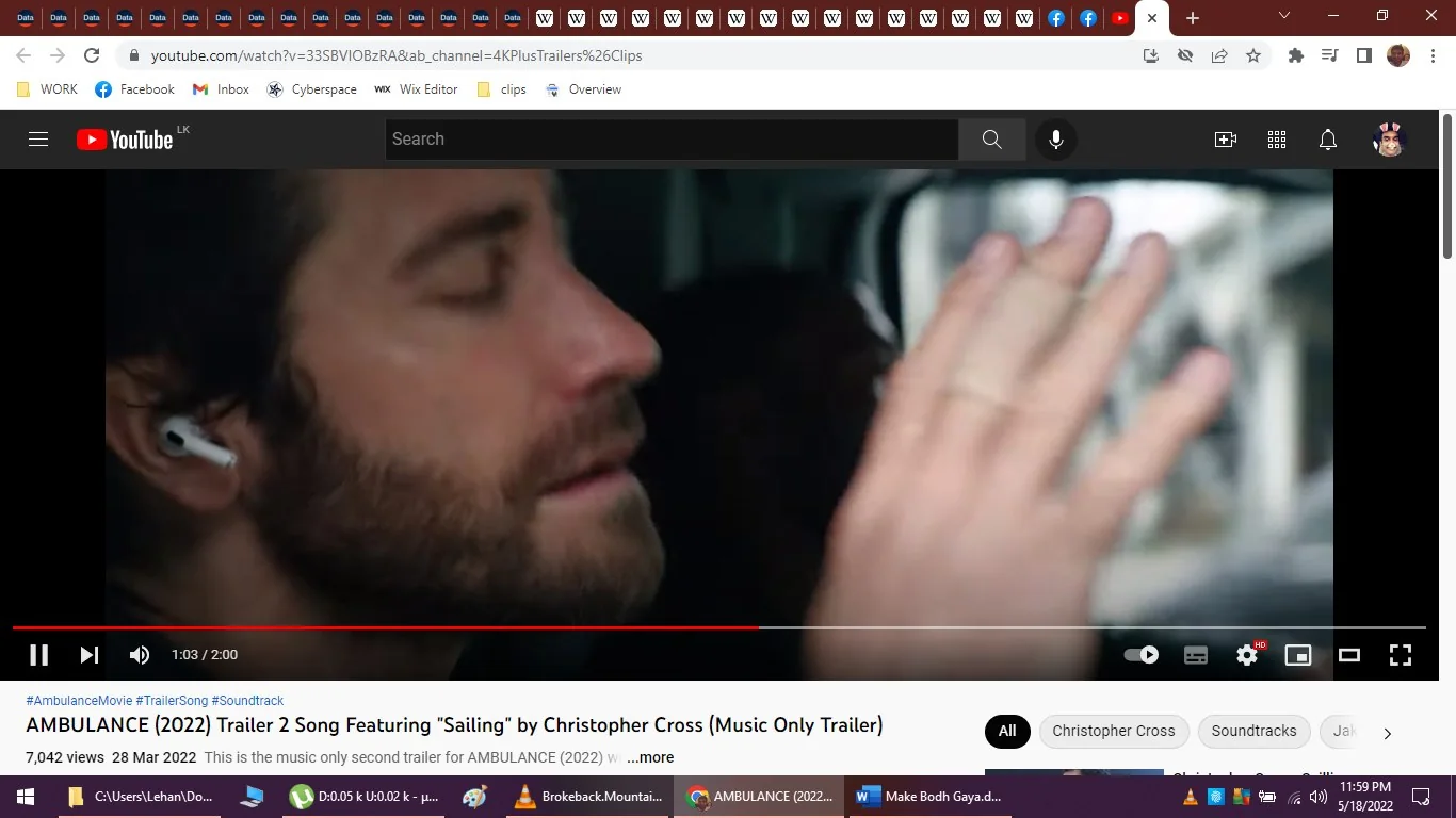 The image is a screenshot from a YouTube video titled "AMBULANCE (2022) Trailer 2 Song Featuring “Sailing” by Christopher Cross (Music Only Trailer)." It shows a close-up of a man with closed eyes, wearing wireless earbuds, seemingly lost in thought or concentrating. His hand is raised near his face, possibly in a gesture of emphasis or focus. The scene has a subdued lighting, typical of an indoor setting, giving it a dramatic and immersive feel. The man has a beard and appears to be in a vehicle, indicated by the blurred background, which suggests movement or travel. The video is from the YouTube channel "4KPlusTrailers&Clips," and the trailer is associated with the film "AMBULANCE (2022)." The image is part of a music-only trailer featuring the song "Sailing" by Christopher Cross, as indicated by the text overlay on the video. The screenshot captures a moment of introspection or intensity, typical of action or thriller film trailers.
- Title: "AMBULANCE (2022) Trailer 2 Song Featuring “Sailing” by Christopher Cross (Music Only Trailer)"
- Channel / profile: "4KPlusTrailers&Clips"
- Site / app: "YouTube"