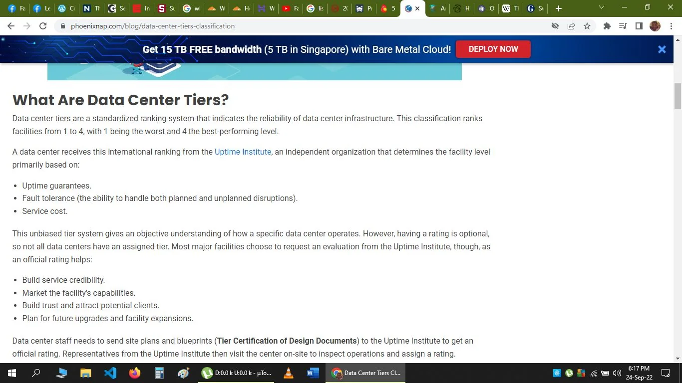The image is a screenshot of an informational webpage from phoenixnap.com discussing data center tiers. The page title, "What Are Data Center Tiers?", is prominently displayed at the top, followed by text explaining the standardized ranking system for data centers. This system ranks facilities from 1 to 4 based on their reliability, with higher numbers indicating better performance. The ranking is primarily determined by the Uptime Institute and considers factors such as uptime guarantees, fault tolerance, and service cost. The text notes that while these ratings are optional, many major facilities pursue them to build credibility and plan for future expansions. The screenshot features a clean and straightforward layout with a white background, black text, and a blue header that includes a promotional banner for cloud services at the top.