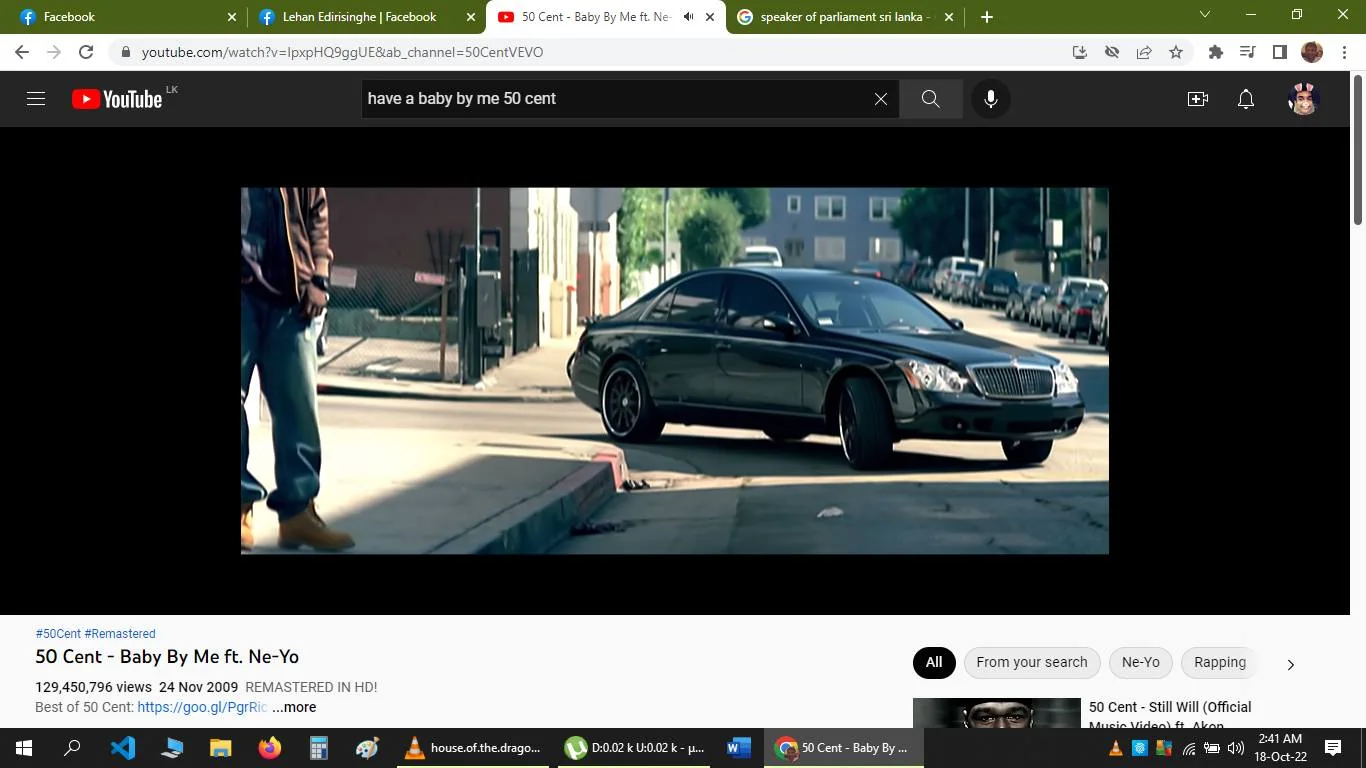 The screenshot shows a scene from a YouTube video titled “50 Cent - Baby By Me ft. Ne-Yo,” hosted on the 50CentVEVO channel. The video currently has over 129 million views and was remastered in HD on November 24, 2009. The scene captures an urban street setting with a focus on a sleek black luxury car parked on the road. Part of a person is visible on the left, wearing casual attire with jeans and tan boots, suggesting a relaxed, everyday street vibe. The background shows a typical city block with buildings and parked cars lining the street, contributing to the urban atmosphere. The lighting is natural, indicating a daytime setting. The image conveys a modern and upscale mood, enhanced by the presence of the luxury vehicle.
- Title: "50 Cent - Baby By Me ft. Ne-Yo"
- Channel / profile: "50CentVEVO"
- Site / app: "YouTube"