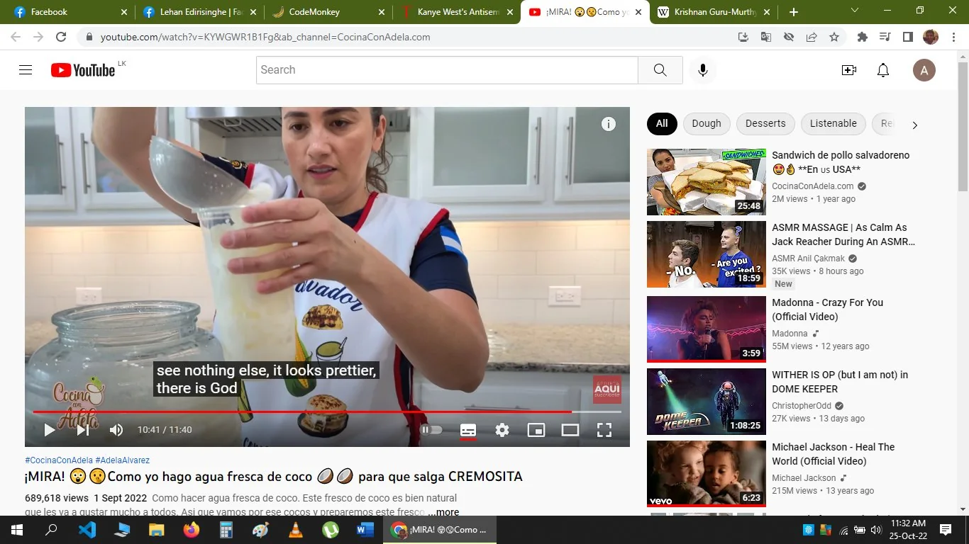 ```
The image is a screenshot from a YouTube video titled "¡MIRA! 😳👌Como yo hago agua fresca de coco 🥥🥥 para que salga CREMOSITA," hosted on the channel "CocinaConAdela." It features a person demonstrating how to make creamy coconut water. The scene is set in a modern kitchen with white cabinets and a light-colored backsplash. The individual is focusing on pouring or mixing ingredients into a container. The thumbnail and surrounding interface indicate it's a cooking tutorial, with related video thumbnails on the right. The person is wearing an apron with the design and text related to "Salvador," likely indicating a cultural or recipe theme. The video has over 689,000 views, suggesting its popularity. Captions are visible, displaying text in English, translating a part of the host's dialogue. The overall mood is educational and engaging, designed to instruct viewers on making a specific beverage.