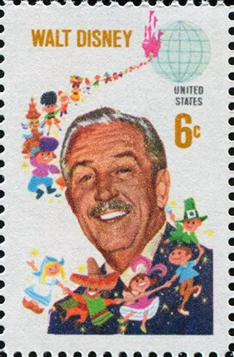 The image shows a colorful postage stamp featuring Walt Disney. Walt Disney's headshot is prominently displayed in the center, smiling warmly. Above his image, the name "WALT DISNEY" is printed in bold, golden letters. To the right, the text "UNITED STATES" is visible along with the denomination "6c" indicating the value of the stamp. The background is filled with vibrant, whimsical illustrations of various characters, likely representing different nationalities and cultures, which are reminiscent of Disney's inclusive storytelling and animation style. A globe with a trail of stars is also part of the background design, enhancing the theme of global unity and imagination. The stamp is bordered by perforated edges typical of postage stamps. The overall color scheme is lively, showcasing a mix of bright colors and pastel tones that capture the playful essence associated with Disney's creations.