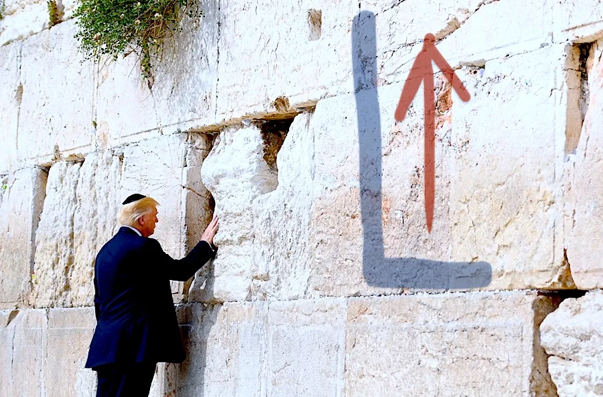 ```
The image shows a figure identified in the hint as Trump, standing in front of a large stone wall, which is part of a historical and religious site. The setting appears to be outdoors, under natural daylight. Trump is wearing a dark suit and a white shirt, along with a black skullcap, which is a traditional head covering worn at this location by many visitors as a sign of respect.
He is positioned near the wall, touching it with his right hand, a common practice at this site. The wall is constructed of large, ancient stones, with some greenery visible growing between them. The surface of the stones is weathered, indicating their age and historical significance. The atmosphere of the scene conveys a sense of solemnity and reflection, with Trump standing quietly and contemplatively. An arrow symbol is drawn on the wall in the image, adding a graphical element that contrasts with the historical backdrop.