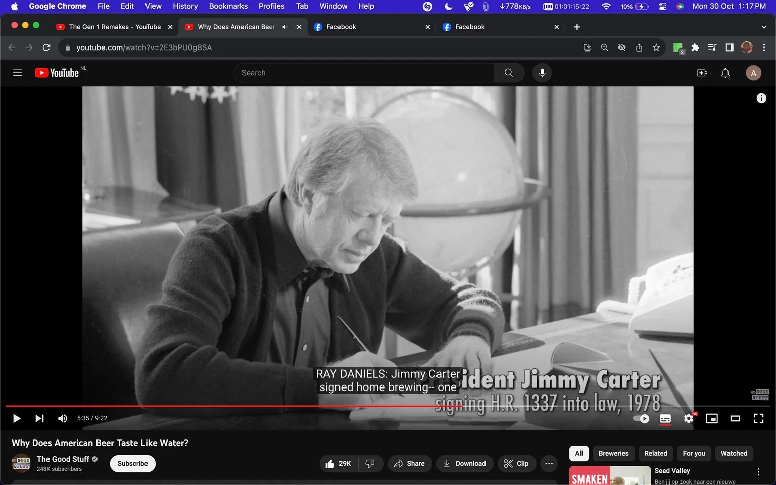 The screenshot captures a historical black and white image from a YouTube video titled "Why Does American Beer Taste Like Water?" featured on the channel "The Good Stuff." The scene shows President Jimmy Carter sitting at a desk in an office setting, captured during a moment of focus as he appears to be signing a document. In the background, there's a globe and some drapery, adding a formal office ambiance. The video subtitle reads, "RAY DANIELS: Jimmy Carter signed home brewing--one," and the on-screen text indicates "President Jimmy Carter signing H.R. 1337 into law, 1978." This image is part of a discussion about the legislation that influenced American beer production, with particular emphasis on home brewing. The overall tone of the image is serious and reflective, highlighting a significant moment in brewing history.