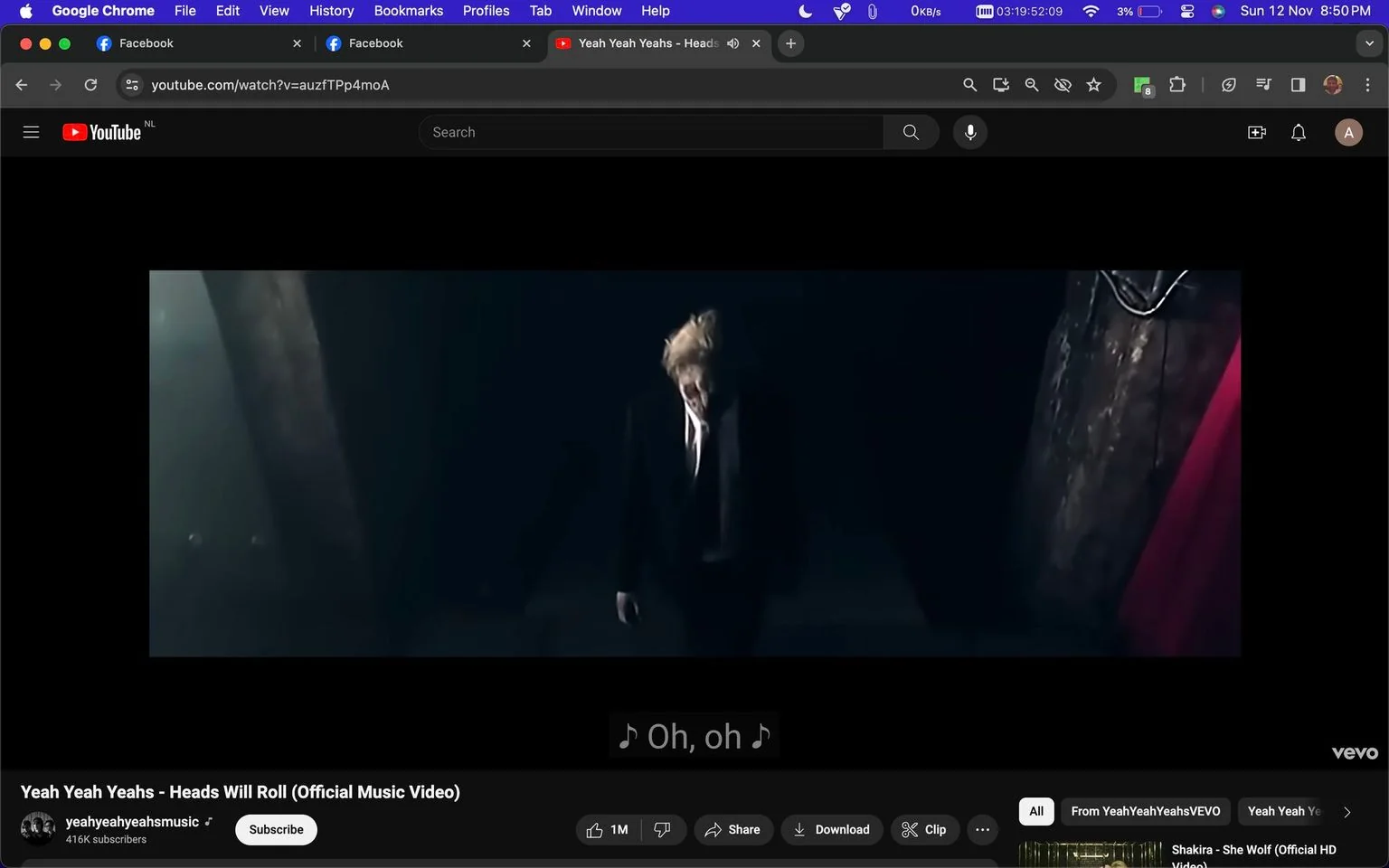 The image is a screenshot from a YouTube video titled "Yeah Yeah Yeahs - Heads Will Roll (Official Music Video)" on the channel "yeahyeahyeahsmusic." The scene is dark and dramatic, featuring a person dressed in a formal suit and tie, standing in a dimly lit space. The lighting is low, casting shadows that enhance the somber and intense mood of the video. The individual appears to be in motion, perhaps walking or dancing, which aligns with the dynamic nature of a music video. The background is obscured, focusing attention on the figure in the foreground. Subtitles are present at the bottom of the screen, displaying the lyrics "♪ Oh, oh ♪," indicative of a musical performance. The video is from the band Yeah Yeah Yeahs, and the visual style reflects the band's edgy and artistic aesthetic.
- Title: "Yeah Yeah Yeahs - Heads Will Roll (Official Music Video)"
- Channel / profile: "yeahyeahyeahsmusic"
- Site / app: "YouTube"
- Captions / subtitles: "♪ Oh, oh ♪"