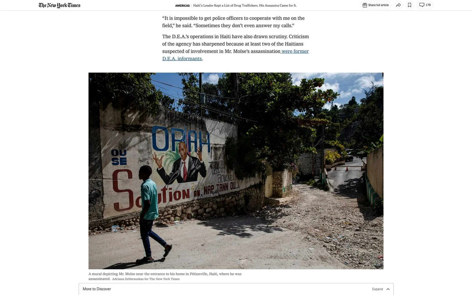 The image is a screenshot from an article on The New York Times. The title of the article is "Haiti’s Leader Kept a List of Drug Traffickers. His Assassins Came for It." It discusses the assassination of Haiti's leader and issues related to drug trafficking. The photograph depicted in the article shows a mural of Mr. Moïse painted on a wall near the entrance to his home in Pétionville, Haiti, where he was assassinated.
The mural features Mr. Moïse in a suit, gesturing with an open hand, and includes text such as "OPAH" and "Solution 2020." The scene captures a street setting with a person walking past, casting a shadow on the ground. The surroundings are lush with greenery, and there is a clear blue sky above, indicating a bright, sunny day. The mural is painted with vibrant colors, contrasting with the natural tones of the street and foliage. The setting feels somber given the context of the article, reflecting on the political tension and turmoil in the region.