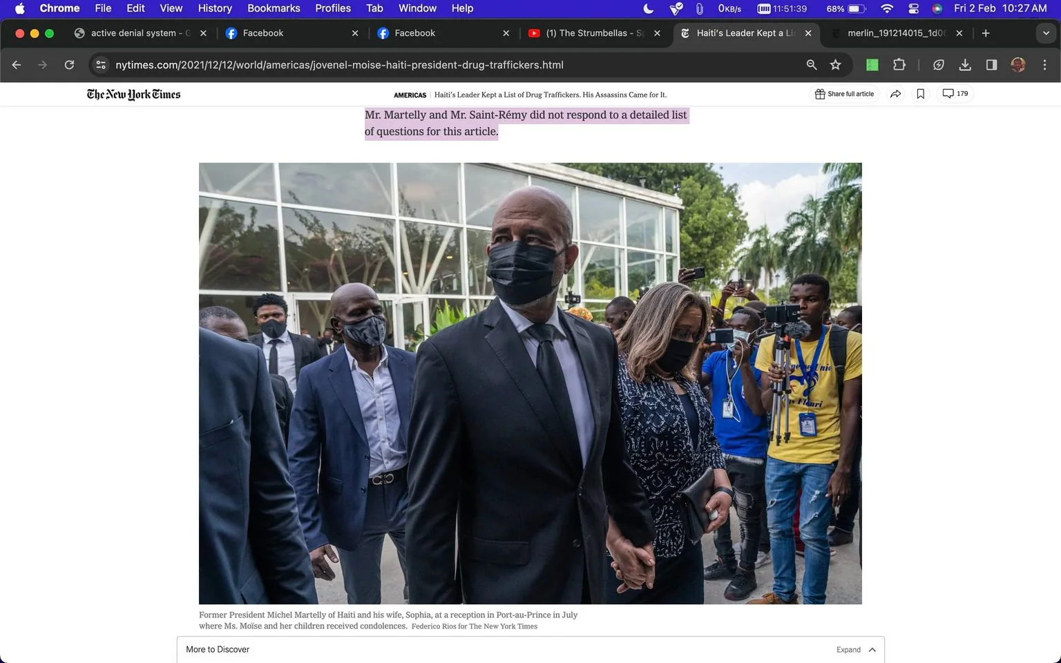 The image shows former President Michel Martelly of Haiti and his wife, Sophia, at a reception in Port-au-Prince. They are surrounded by a crowd, including media personnel capturing the event. Michel Martelly is dressed in a formal black suit and tie, wearing a black mask, and is holding hands with Sophia, who is also wearing a mask and a patterned jacket. The scene conveys a somber mood as it takes place at an event where Ms. Moise and her children received condolences. The backdrop features a glass building, and tropical plants are visible, suggesting an outdoor setting in a warm climate. Several photographers and videographers are present, some wearing blue shirts, pointing cameras towards the couple. The lighting is natural, indicating the event occurs during the daytime. The screenshot is part of an article from The New York Times titled "Haiti’s Leader Kept a List of Drug Traffickers. His Assassins Came for It."