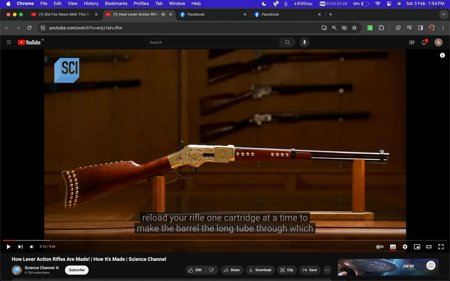 The screenshot is from a YouTube video titled "How Lever Action Rifles Are Made! | How It’s Made | Science Channel" on the Science Channel's profile. It features a prominently displayed lever-action rifle, which is the central focus of the image. The rifle is positioned horizontally on a wooden stand, highlighting its intricate design. The rifle has a polished wooden stock with decorative metal studs, and its metal parts are engraved with intricate patterns, showcasing craftsmanship. The background features a wooden wall with multiple rifles mounted, adding context to the setting as a display or museum-like environment. The lighting is warm, enhancing the wooden tones and metallic sheen of the rifle. Subtitles on the screen read, "reload your rifle one cartridge at a time to make the barrel the long tube through which," indicating an explanation of the rifle's mechanics. The video aims to educate viewers about the manufacturing process and mechanics of lever-action rifles.