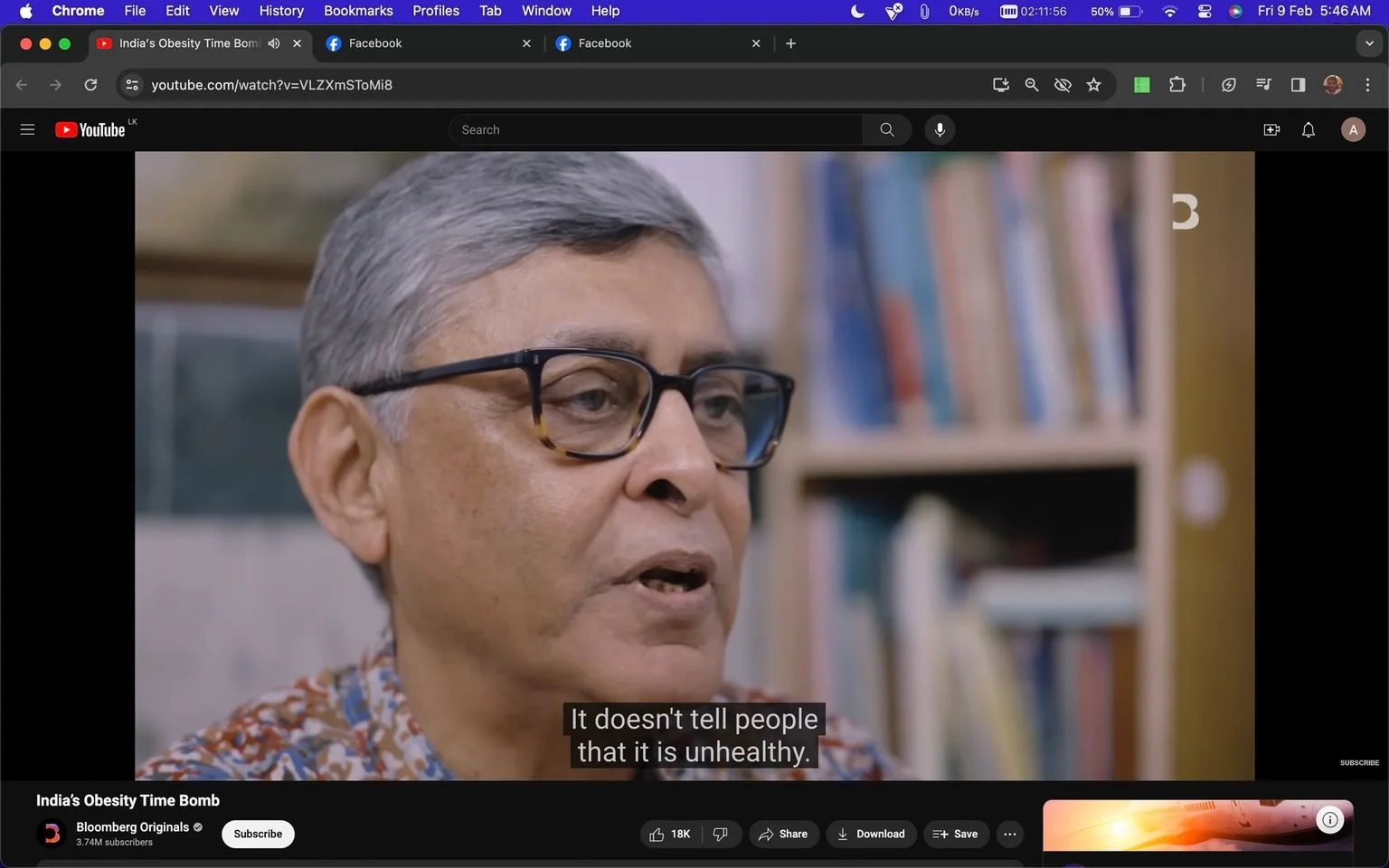 1) Rich description:
The image is a video frame from a YouTube video titled "India's Obesity Time Bomb" on the channel Bloomberg Originals. The setting is an indoor interview, with a person speaking in front of a bookshelf filled with various books. The individual has short gray hair and is wearing glasses with a dark frame. They are dressed in a patterned shirt, suggesting a casual or semi-formal environment. The expression on their face is serious, indicating a discussion on a significant topic. The background is softly blurred, focusing attention on the speaker. The lighting is natural and even, contributing to a neutral and informative atmosphere. The video frame includes subtitles, with the line "It doesn't tell people that it is unhealthy," highlighting a point being discussed about public health perceptions. The interface shows typical YouTube controls and engagement options like subscribe, share, and download.
2) On-screen text block:
- Title: "India's Obesity Time Bomb"
- Channel / profile: "Bloomberg Originals"
- Site / app: "YouTube"
- Captions / subtitles: "It doesn't tell people that it is unhealthy."