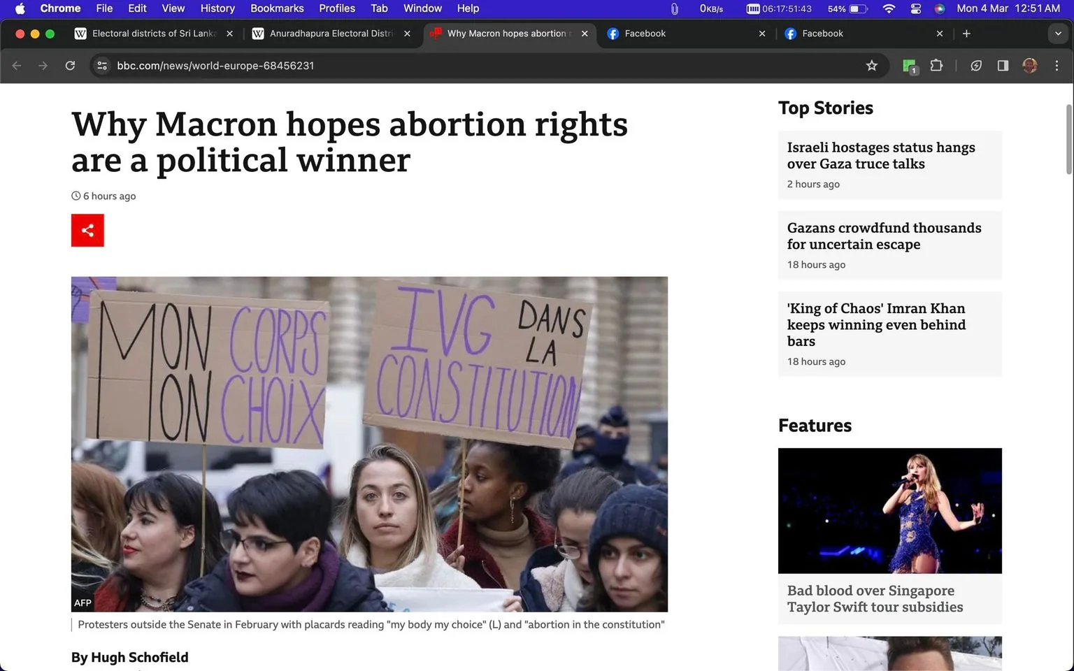 The screenshot is from the BBC News website, featuring an article titled "Why Macron hopes abortion rights are a political winner." The article, written by Hugh Schofield, explores how Emmanuel Macron views abortion rights as a potential political advantage. The image shows a group of protesters, mostly women, holding signs in a demonstration. The placards display messages in French, with one reading "MON CORPS MON CHOIX" (translated as "my body my choice") and another stating "IVG DANS LA CONSTITUTION" (translated as "abortion in the constitution"). This gathering appears to be outside a governmental building, possibly in France.
The protesters are dressed in winter attire, suggesting it is a cold day. Their expressions range from determined to thoughtful, indicating their serious stance on the issue. The overall mood of the scene is one of activism and advocacy. The BBC News website also features a sidebar with top stories and other features, highlighting international political events and cultural news, including a feature about Taylor Swift's tour subsidies in Singapore.