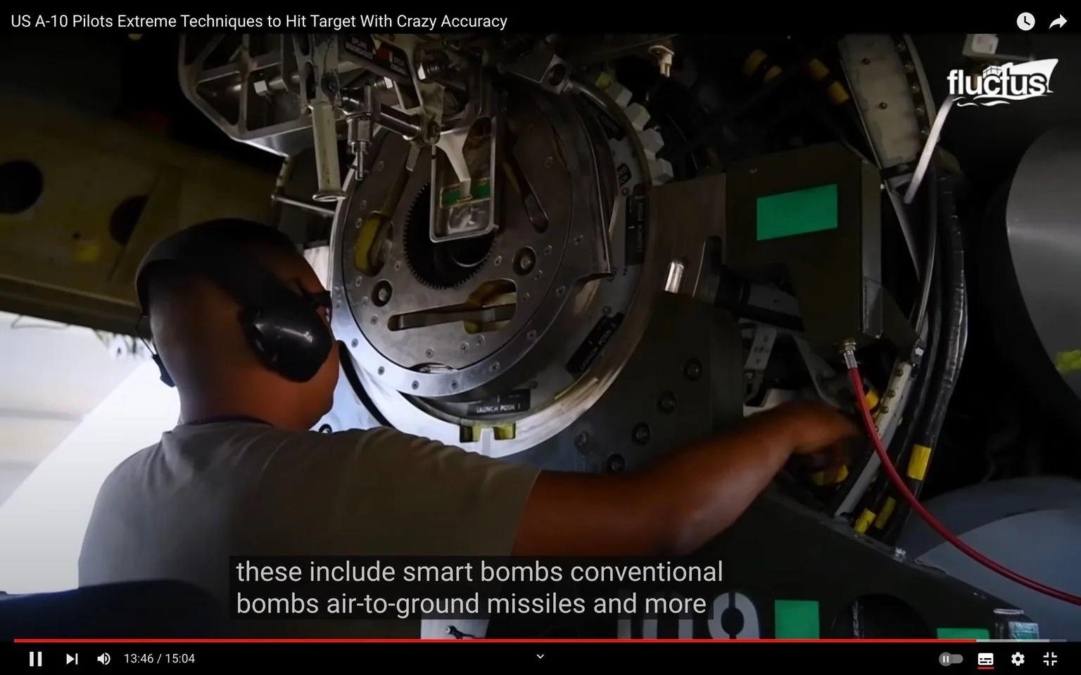 The video frame shows a mechanic working inside the belly of an aircraft, specifically dealing with the internal components. The individual is wearing hearing protection, indicating the noisy environment typical of aircraft maintenance areas. The focus of the image is on a large mechanical assembly with gears and various components, likely part of the A-10 aircraft's weapons system. The lighting is somewhat dim, suggesting the interior of a maintenance hangar. The mechanic appears to be adjusting or inspecting part of the system, highlighting the technical expertise required for such tasks. The machinery is complex, with visible wires and labels, underscoring the sophistication of military aircraft systems. The subtitle mentions various types of munitions, such as smart bombs and air-to-ground missiles, relevant to the A-10’s capabilities. This scene gives insight into the meticulous and skilled work involved in maintaining and preparing military aircraft for operations.
- Title: "US A-10 Pilots Extreme Techniques to Hit Target With Crazy Accuracy"
- Channel / profile: "fluctus"
- Site / app: "YouTube"
- Captions / subtitles: "these include smart bombs conventional bombs air-to-ground missiles and more"