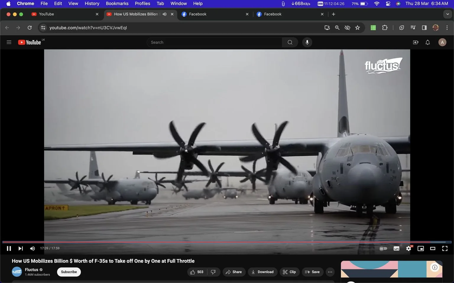 The video frame depicts a scene captured at an airfield, showcasing several military aircraft on a runway. The composition is dominated by multiple large planes, possibly C-130 Hercules aircraft, lined up in a row, their propellers prominently visible. The setting appears to be overcast, with a gray sky casting a muted light over the scene, enhancing the military, utilitarian atmosphere. The aircraft are painted in standard military colors, blending into the dreary background, emphasizing their functional design.
In the foreground, one plane is positioned prominently, facing the viewer, with its propellers slightly blurred to suggest readiness for takeoff or recent landing. The runway is wet, reflecting the aircraft and adding a dynamic visual element to the scene. The video is identified as being from YouTube, under the title "How US Mobilizes Billion $ Worth of F-35s to Take off One by One at Full Throttle," uploaded by the channel "Fluctus." The Fluctus logo is visible in the top right corner, identifying the content creator. The video likely explores military aviation logistics, focusing on the operation and management of advanced aircraft.