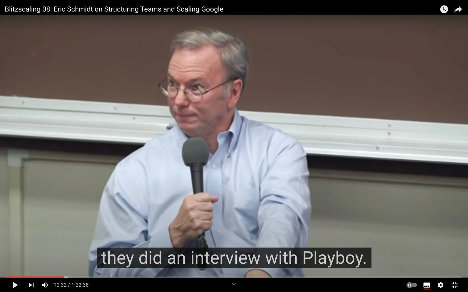 Eric Schmidt is featured in this video frame from a YouTube video titled "Blitzscaling 08: Eric Schmidt on Structuring Teams and Scaling Google." In this indoor setting, Eric Schmidt is seated, holding a microphone, indicating he is engaged in a discussion or lecture. He is dressed in a light blue shirt and has glasses, giving him a professional appearance. The background includes a brown wall and a whiteboard, typical of a lecture or conference room environment. His expression appears thoughtful as he listens or reflects on a point. The frame includes subtitles that read, "they did an interview with Playboy," suggesting the discussion involves media or public relations topics. The lighting is neutral, allowing clear visibility of his features and surroundings. This scene is part of a broader conversation on business strategies and leadership, featuring Eric Schmidt's insights.
- Title: "Blitzscaling 08: Eric Schmidt on Structuring Teams and Scaling Google"
- Site / app: "YouTube"
- Captions / subtitles: "they did an interview with Playboy."