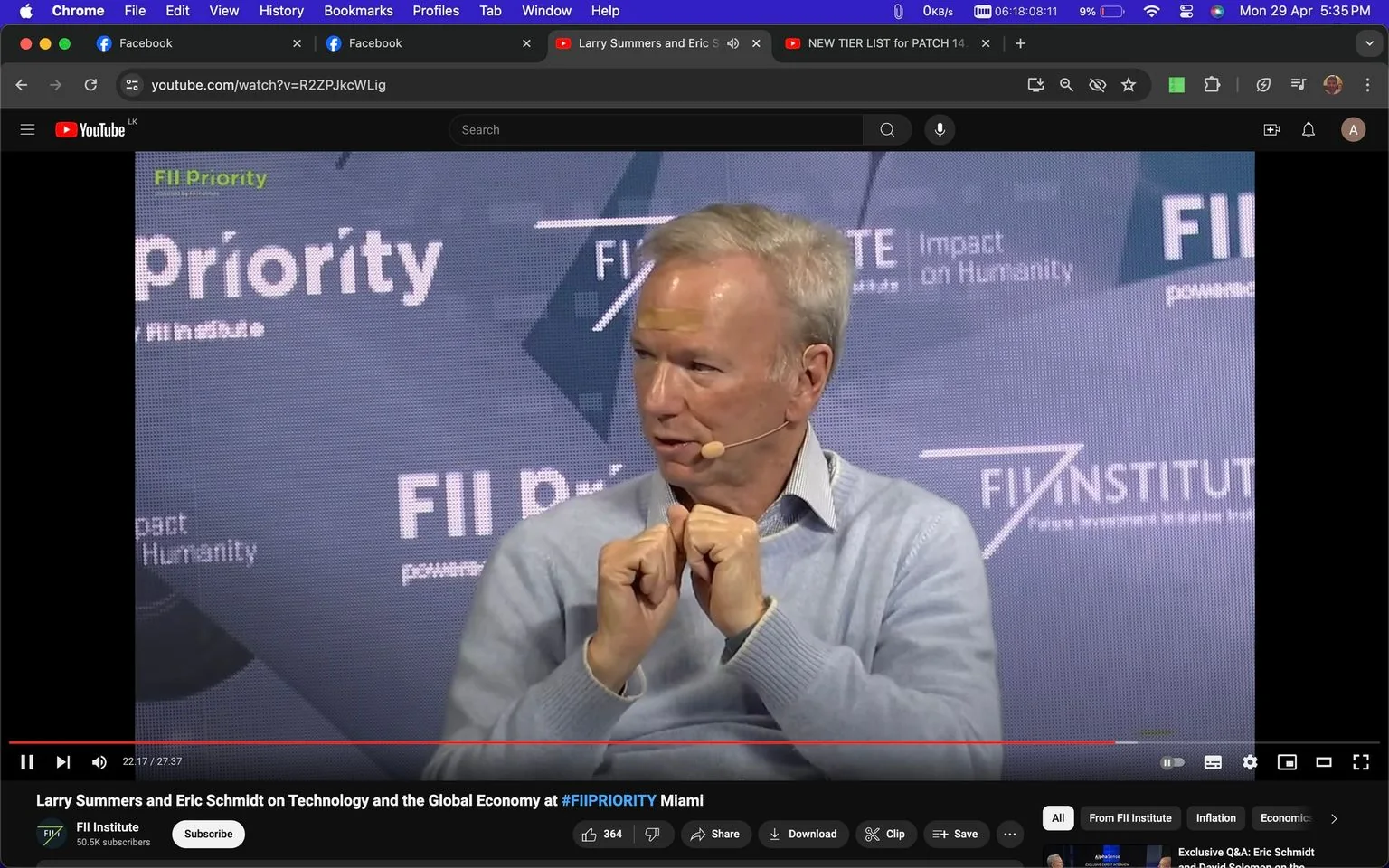 Eric Schmidt is depicted in this screenshot from a YouTube video titled "Larry Summers and Eric Schmidt on Technology and the Global Economy at #FIIPRIORITY Miami," hosted on the FII Institute channel. The setting is a formal conference or panel discussion, indicated by the backdrop displaying "FII Priority" and "Impact on Humanity," along with the "FII INSTITUTE" branding. Eric Schmidt is dressed in a light gray sweater over a collared shirt, with a lapel microphone attached, suggesting he is actively participating in the discussion. His posture, with hands clasped and a thoughtful expression, indicates engagement in a conversation or presentation. The image is well-lit, with a focus on Schmidt against a branded backdrop, emphasizing the professional and intellectual atmosphere of the event. The video interface is visible, showing the video's progress bar, and the YouTube platform interface with options for subscribing, liking, and sharing the content.