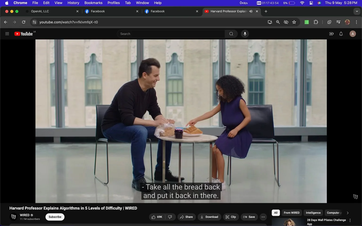 The image is a screenshot from a YouTube video titled "Harvard Professor Explains Algorithms in 5 Levels of Difficulty | WIRED." It features a scene indoors where a Harvard professor is interacting with a young girl. They are seated at a round table, which has a loaf of bread, a jar of what appears to be jam, and some plastic packaging. The professor is wearing a black sweater and jeans, while the girl is dressed in a dark purple dress with white sneakers.
The setting appears to be a modern, well-lit room with large windows in the background, suggesting a sophisticated educational environment. The professor is smiling and appears engaged in a friendly and educational interaction with the child. The girl is reaching for the bread, possibly as part of a demonstration or explanation related to algorithms, which fits the theme of simplifying complex topics for different audiences. The video is presented by WIRED, focusing on explaining concepts at various levels of difficulty.
- Title: "Harvard Professor Explains Algorithms in 5 Levels of Difficulty | WIRED"
- Channel / profile: "WIRED"
- Site / app: "YouTube"
- Captions / subtitles: "Take all the bread back and put it back in there."