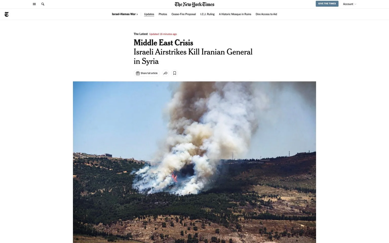 The image is a screenshot from The New York Times website, featuring an article titled "Middle East Crisis: Israeli Airstrikes Kill Iranian General in Syria." The headline is prominent at the top, conveying the urgent nature of the news. Below the headline, there is a photograph showing a hilly landscape engulfed in smoke. The smoke is thick and billowy, rising high into the clear blue sky, indicating the aftermath of a fire or explosion.
The landscape is covered with patches of green vegetation and rugged terrain, suggesting a rural or semi-arid setting typical of parts of Syria. The smoke appears to originate from a specific point among the hills, hinting at a recent impact or strike. The overall tone of the image is somber and tense, reflecting the serious nature of the news. The website's design frames the content with minimal distractions, focusing attention on the article's title and the impactful image.
