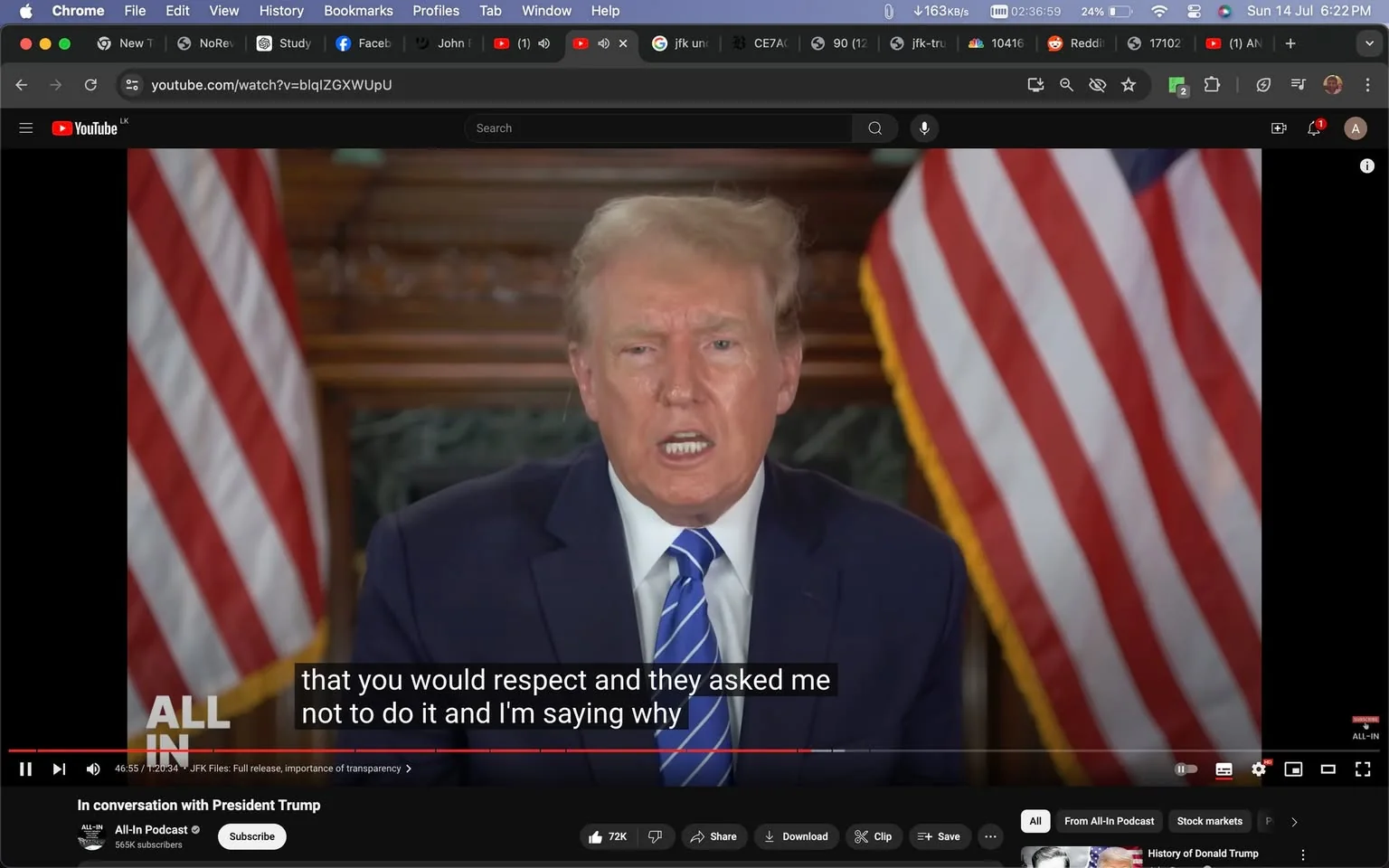 Donald Trump is featured in this YouTube screenshot from a video titled "In conversation with President Trump" on the All-In Podcast channel. He is seated indoors, speaking directly to the camera. His posture is formal, wearing a dark suit, white shirt, and a blue striped tie. The background includes two American flags positioned symmetrically, adding a patriotic atmosphere to the scene. The lighting is soft and evenly distributed, highlighting his expression, which appears earnest and engaged. Captions at the bottom of the image read, “that you would respect and they asked me not to do it and I'm saying why,” providing a snippet of the conversation. The screen includes a red progress bar at the bottom, indicating the video is being played. In the toolbar, options such as "Share," "Download," and "Clip" are visible, suggesting the video content is being actively viewed and interacted with. The YouTube interface shows various tabs and icons, typical of a desktop browser view.