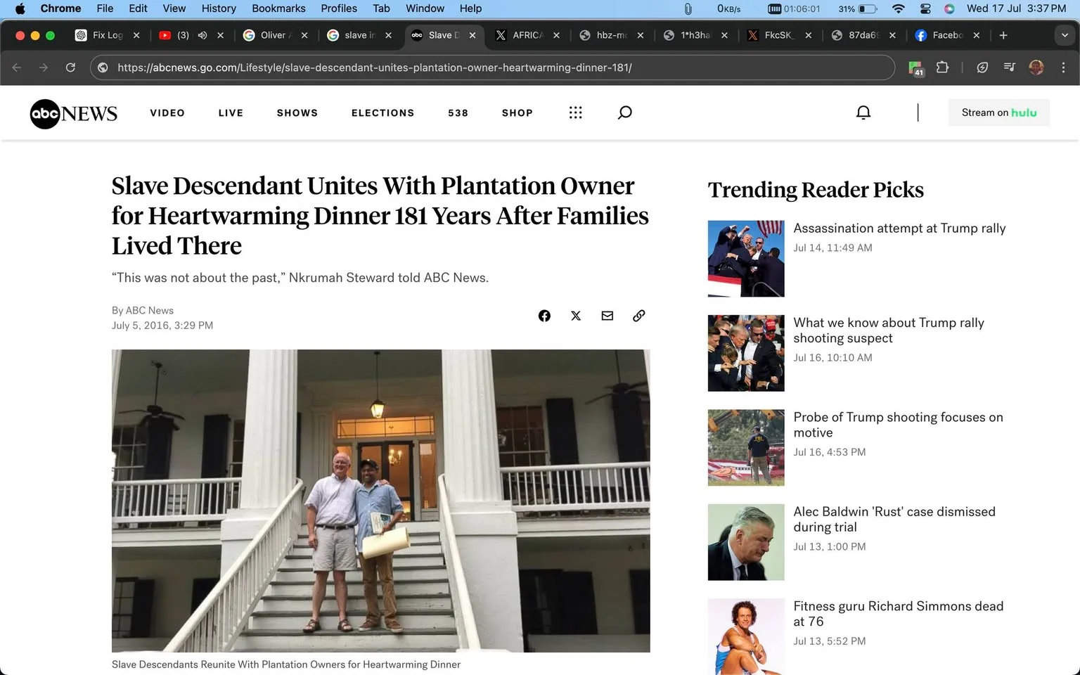 The screenshot shows an article from ABC News with the headline "Slave Descendant Unites With Plantation Owner for Heartwarming Dinner 181 Years After Families Lived There." The article, dated July 5, 2016, features a photograph of two men standing arm in arm on the steps of a grand, historic building with large columns and a porch. The man on the left is wearing a light-colored shirt and shorts, while the man on the right is dressed in a blue shirt and pants, holding a rolled-up paper. They are both smiling, suggesting a positive and warm atmosphere. The building's architecture is evocative of the Southern United States, likely a plantation house, which correlates with the article's subject matter. The staircase and porch are painted white, and the scene is set during the day, as indicated by the lighting. To the right of the article, there are trending news topics listed, including incidents related to Trump rallies and other current events at the time.