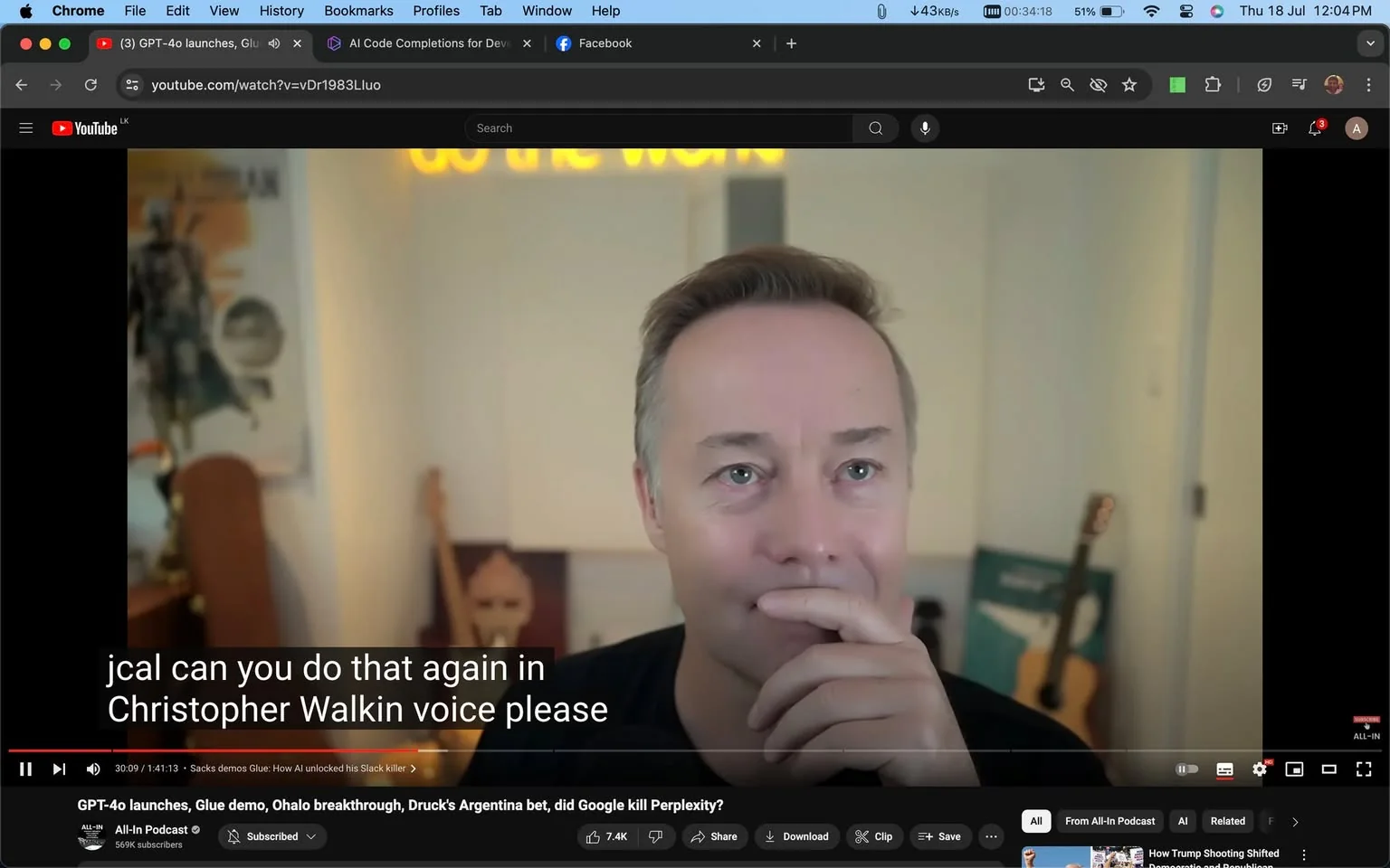 The image is a screenshot from a YouTube video titled "GPT-4o launches, Glue demo, Ohalo breakthrough, Druck's Argentina bet, did Google kill Perplexity?" from the "All-In Podcast" channel. The scene is set indoors, featuring a person sitting in a room with a casual atmosphere. In the background, there is a guitar leaning against the wall and a poster that partially shows an armored figure, possibly from a movie or game. A neon sign reading "GO THE WORK" is partially visible, adding a modern touch to the decor. The person appears to be listening intently or contemplating, with a thoughtful expression and one hand resting near their chin. The video has captions enabled, displaying the subtitle: "jcal can you do that again in Christopher Walkin voice please." The overall mood is relaxed, typical of podcast discussions. The lighting is warm and evenly distributed, enhancing the calm setting.