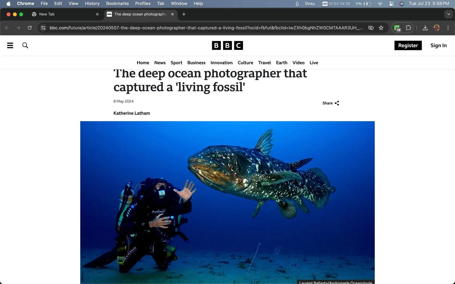 The image is a screenshot from a BBC article titled "The deep ocean photographer that captured a 'living fossil'." The article is credited to Katherine Latham and dated 8 May 2024. The content is presented on the BBC website, recognizable by its layout and logo at the top.
In the main image of the article, an underwater scene is depicted. A diver is on the left, wearing a full scuba diving suit, complete with a mask and oxygen tank. The diver appears to be observing a large coelacanth, a rare fish often referred to as a "living fossil" due to its ancient lineage. The fish is on the right, swimming in clear blue water with its distinctive lobe-finned structure visible. The lighting is bright enough to illuminate both the diver and the fish, highlighting the details of the coelacanth’s scales and fins. The mood of the image conveys a sense of exploration and discovery, typical of deep-sea photography.