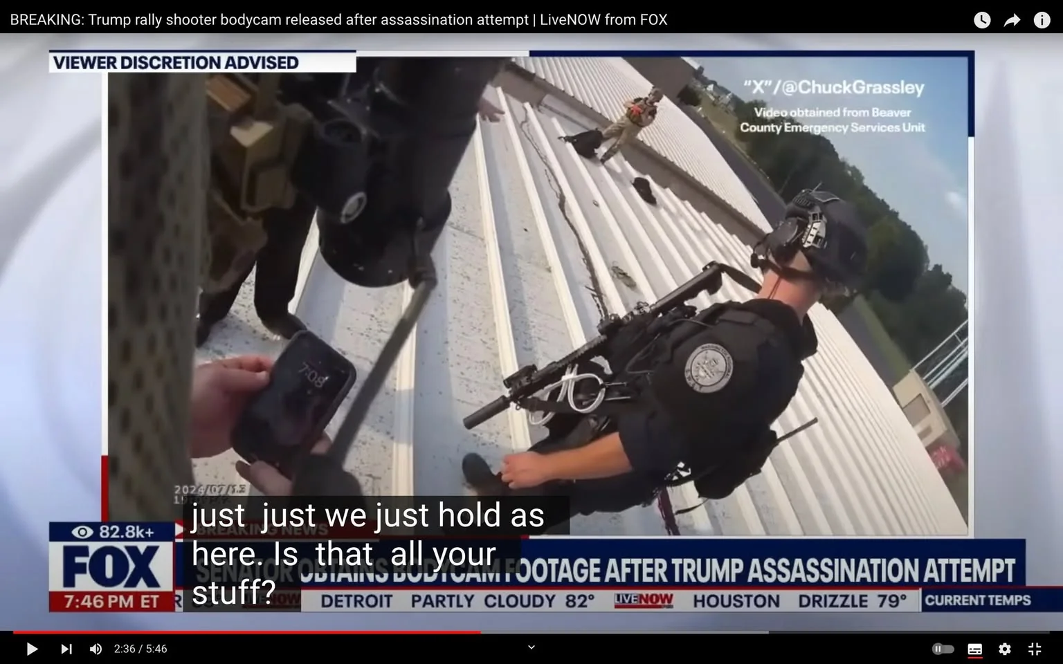 The video frame depicts an intense scene, presumably captured during an emergency situation. It shows law enforcement officers positioned on a rooftop, with one officer in the foreground dressed in tactical gear, including a helmet and a rifle. The officer appears alert and prepared, adding to the tense atmosphere of the setting. The background features another individual standing on the roof, engaging with officers, possibly in a negotiation or standoff, indicated by their body language and positioning.
The image is part of a news broadcast titled "BREAKING: Trump rally shooter bodycam released after assassination attempt | LiveNOW from FOX." This suggests the footage is related to a significant and potentially dangerous event involving a Trump rally. Overlay text identifies the source of the video as obtained from the Beaver County Emergency Services Unit, with a social media handle "@ChuckGrassley" also visible.
The lower third of the screen provides more context, branding it as a FOX News segment with current weather conditions displayed. Subtitles overlaying the image capture dialogue, indicating a moment of assessment or instruction among the officers. The visual elements, combined with the text, convey a sense of immediacy and gravity, typical of breaking news events involving security and law enforcement operations.
