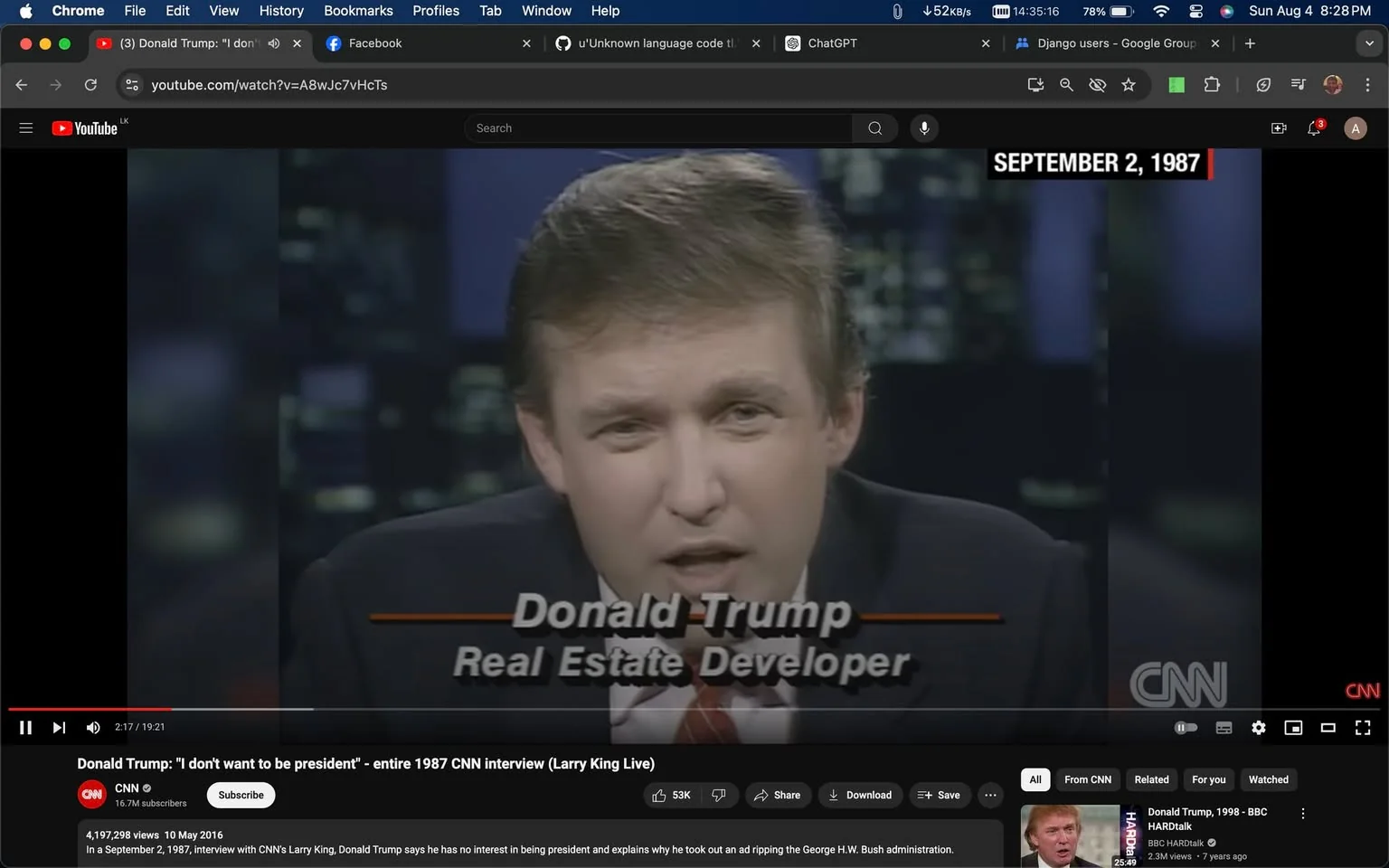 In this video frame, Donald Trump is being interviewed on a television program by CNN, as indicated by the logo in the bottom corner. The scene is set indoors in what appears to be a studio environment, characterized by dim lighting and a blurred cityscape in the background. Donald Trump, labeled as a "Real Estate Developer" in on-screen text, is speaking directly to the camera. He is wearing a dark suit with a white shirt and a striped tie, projecting a formal and composed demeanor. The date "SEPTEMBER 2, 1987" is displayed at the top right corner, situating this moment in the late 1980s. The frame captures a moment from an interview on "Larry King Live," as part of a conversation where Donald Trump discusses his disinterest in pursuing a presidential role. The YouTube interface is visible, showing the video title, view count, and options such as like, share, and download.