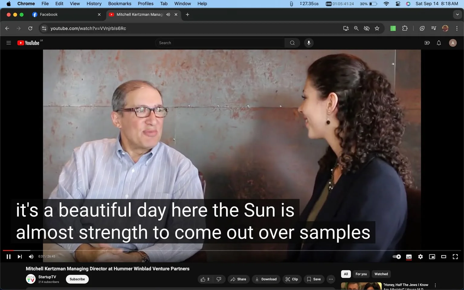 The image is a video frame from an interview posted on YouTube, featuring Mitchell Kertzman, who is identified as the Managing Director at Hummer Winblad Venture Partners. It appears on the channel StartupTV. The setting is indoors, with a muted, industrial-style backdrop, possibly metal or concrete, which aligns with the professional and formal tone of the conversation.
Mitchell Kertzman, wearing glasses and a light striped shirt, is seated on the left, turned slightly towards the woman on the right. His posture is relaxed, suggesting an informal and engaging discussion. The woman, who has curly hair tied back, is wearing a dark blazer and jewelry, giving a polished and professional appearance. Both individuals are smiling, indicating a positive and friendly atmosphere.
The title of the video is displayed at the bottom, clearly naming Mitchell Kertzman. The video player interface shows standard controls at the bottom, with a visible caption: "it's a beautiful day here the Sun is almost strength to come out over samples." The lighting in the scene is balanced, capturing the subjects clearly against the neutral background. This frame captures a moment of dialogue during what seems to be an interview focusing on business or venture capital topics.