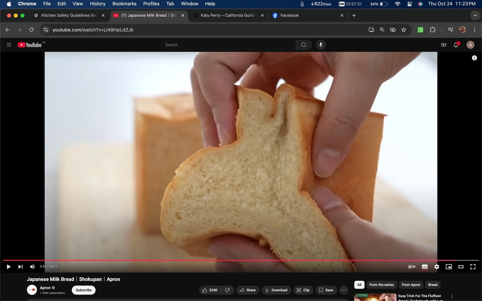 The scene is a close-up shot from a YouTube video titled "Japanese Milk Bread | Shokupan | Apron," hosted on the Apron channel. The video focuses on a person gently tearing a slice of soft, fluffy milk bread, revealing its airy and tender texture. The background is softly blurred to emphasize the bread, which has a light golden-brown crust and a creamy white interior. The hands handling the bread are visible, suggesting a careful and delicate demonstration. The overall lighting is bright and soft, creating a warm and inviting atmosphere typical of food videos aimed at showcasing the texture and quality of the bread. The video interface includes a typical YouTube layout with options for like, share, and subscribe, and the video timestamp is at 9:41 of a 10:11 length video. The page indicates a high level of engagement with 324K likes.