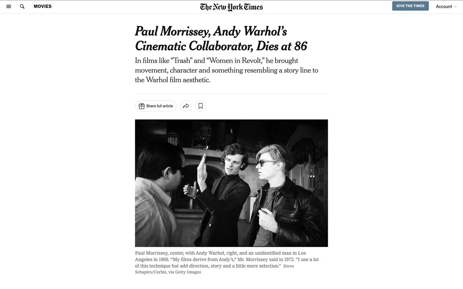 Paul Morrissey and Andy Warhol are featured in this black and white photograph, set in Los Angeles in 1966. The image captures a moment of engagement, with Paul Morrissey at the center, gesturing with his hands as if explaining or discussing something significant. Andy Warhol is on the right, wearing dark sunglasses and a leather jacket, exuding his iconic cool demeanor. An unidentified man stands to the left, facing Morrissey. The setting appears to be indoors, possibly on a film set or a venue with ornate architecture visible in the background. The lighting is natural, casting soft shadows that add to the historical ambiance of the photograph. The mood is one of artistic collaboration, highlighting the creative synergy between Morrissey and Warhol. The image accompanies an obituary headline about Paul Morrissey’s passing at age 86, reflecting on his contributions to films like “Trash” and “Women in Revolt,” where he infused movement and storyline into the Warhol film aesthetic.
- Title: "Paul Morrissey, Andy Warhol’s Cinematic Collaborator, Dies at 86"
- Site / app: "The New York Times"
- Captions / subtitles: "Paul Morrissey, center, with Andy Warhol, right, and an unidentified man in Los Angeles in 1966."