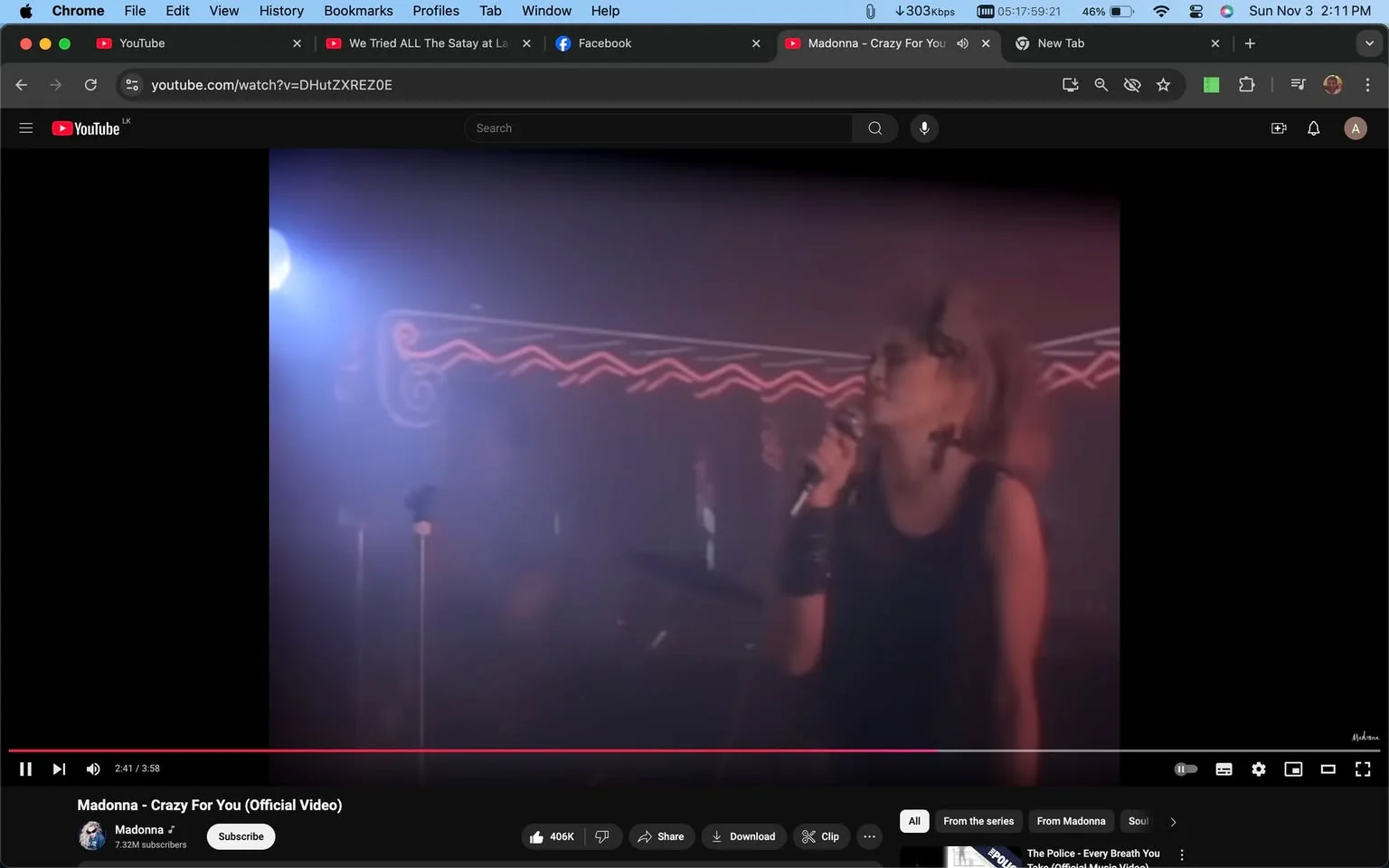1) The screenshot captures a scene from the music video "Madonna - Crazy For You (Official Video)" on YouTube. The image shows a performance setting with Madonna, as identified from the hint, holding a microphone on stage. She is wearing a black sleeveless outfit, accessorized with prominent earrings and a wristband. Her hair is styled in a voluminous manner typical of the 1980s fashion. The background features neon lighting, casting a colorful glow that adds to the concert atmosphere. The stage is dimly lit with a blue spotlight visible on the left side, contributing to a mystic, intimate ambiance. The overall mood is energetic yet romantic, fitting the tone of the song being performed. Madonna's posture suggests she is passionately engaged in singing. The setting evokes nostalgia for 1980s pop music culture. The video interface shows standard YouTube controls, with the title and channel name clearly visible.
2) On-screen text block:
- Title: "Madonna - Crazy For You (Official Video)"
- Channel / profile: "Madonna"
- Site / app: "YouTube"