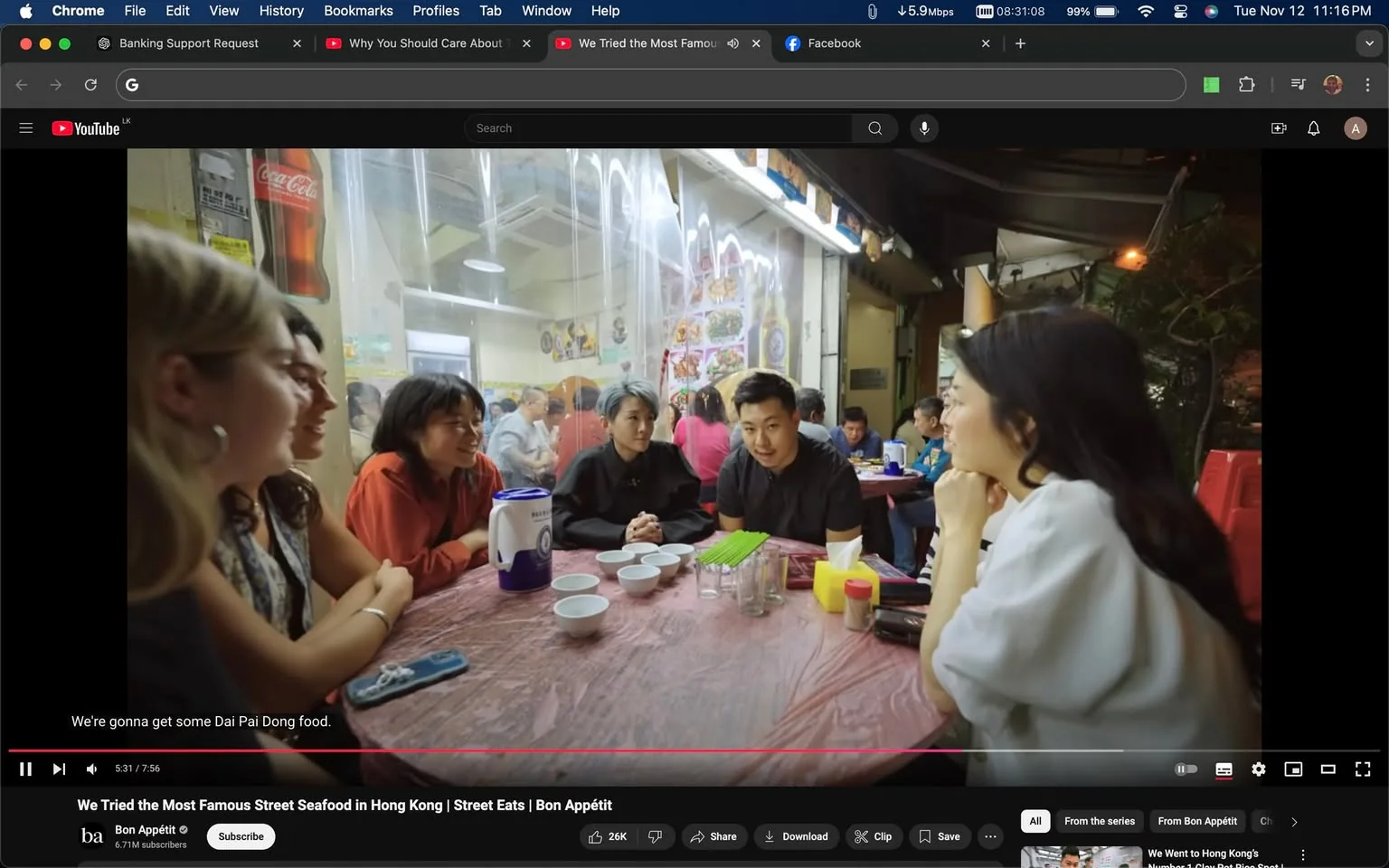 The image is a video frame from a YouTube video titled "We Tried the Most Famous Street Seafood in Hong Kong | Street Eats | Bon Appétit," featured on the Bon Appétit channel. It captures a lively scene inside a casual dining setting, possibly a dai pai dong, which is a type of open-air food stall in Hong Kong. The setting appears informal, with a plastic tablecloth and utensils placed on the table.
Five people are gathered around a table, engaged in conversation. Their expressions suggest they are enjoying the moment, possibly in anticipation of a meal. In the background, other patrons are visible, contributing to the bustling atmosphere typical of a popular eatery. Notable details include a Coca-Cola advertisement on the wall and various food images displayed, which add to the authentic street food ambiance. Lighting is warm, typical of indoor settings with artificial lights. The video frame has a subtitle at the bottom stating, "We're gonna get some Dai Pai Dong food," indicating the group’s culinary objective.