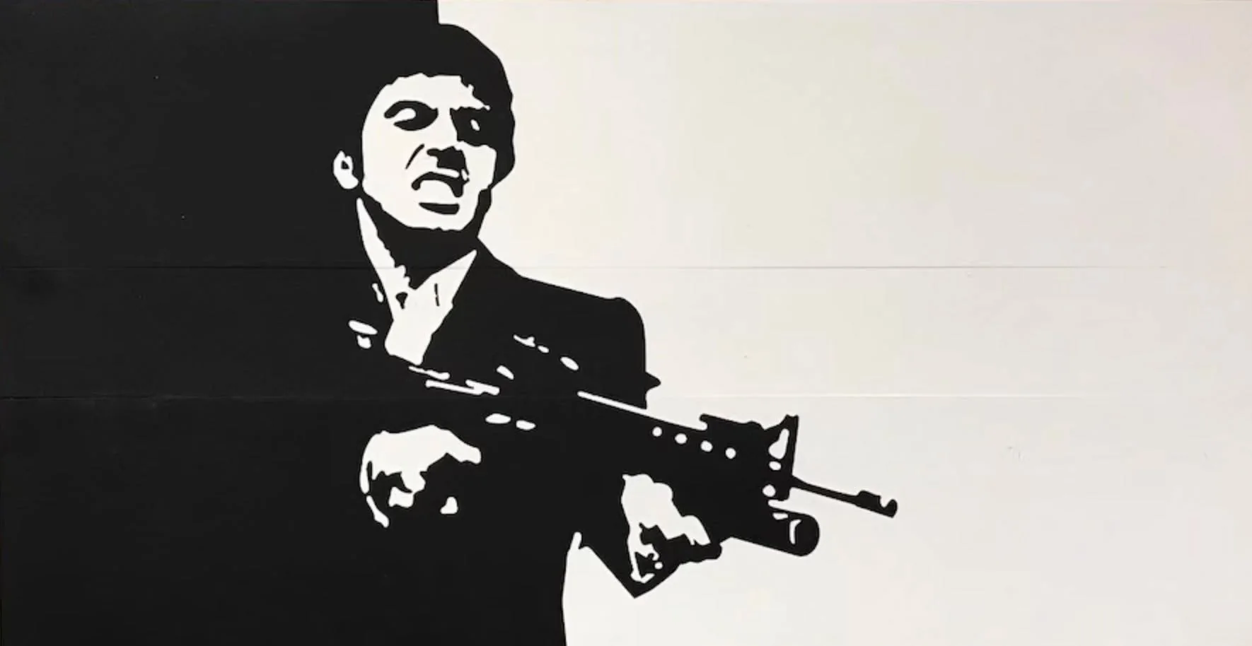 The image features a stylized black-and-white illustration of a man holding a firearm. The figure is depicted in a stark contrast, with the left side of the image being predominantly black and the right side being white. The man is wearing a suit, which is illustrated in black, and his facial expression appears intense, suggesting aggression or determination. 

He is positioned slightly to the right, with his body facing forward. The firearm, which resembles an assault rifle, is held in both hands, pointed outward. The details of the weapon are minimal but suggest a realistic representation. The man's hair is short and slicked back, and his facial features are simplified, focusing on the mouth and eyes, which convey a strong emotion.

The background is divided into two colors: black on the left and white on the right, creating a dramatic effect that emphasizes the figure. There are no visible text, logos, or other identifiable objects in the image. The overall composition is striking, utilizing high contrast to draw attention to the central figure and evoke a sense of tension.

The setting is abstract, with no specific environmental context provided, focusing solely on the figure and the stark color contrast. The image does not include any additional elements or context that would indicate a particular location or event.