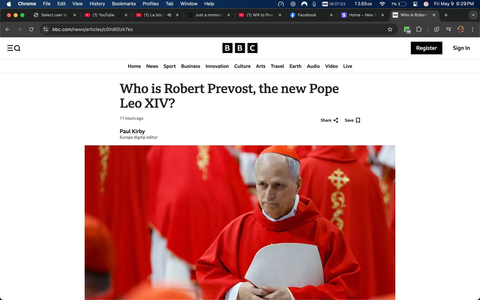 The image displays a webpage from the BBC news site, featuring an article titled "Who is Robert Prevost, the new Pope Leo XIV?" The headline is prominently displayed at the top of the page, followed by a timestamp indicating the article was published 11 hours ago. The author's name, Paul Kirby, is noted as the Europe digital editor.

In the image, there is a photograph of a man dressed in a red robe, which is characteristic of a cardinal in the Catholic Church. He has short, gray hair and is holding a white document or folder in his hands. His expression appears serious and contemplative as he looks slightly downward. The background consists of other individuals dressed in similar red robes, suggesting a religious or ceremonial setting, likely within a church or during a formal event.

The webpage layout includes a navigation bar at the top with options for "Home," "News," "Sport," "Business," "Innovation," "Culture," "Arts," "Travel," "Earth," "Audio," "Video," and "Live." There are also icons for sharing the article and saving it, along with a "Register" and "Sign In" option on the right side.

The overall color scheme of the webpage is predominantly white with red accents, reflecting the theme of the article and the attire of the individuals depicted. The image conveys a formal and significant moment related to the Catholic Church, likely highlighting the appointment of a new pope.