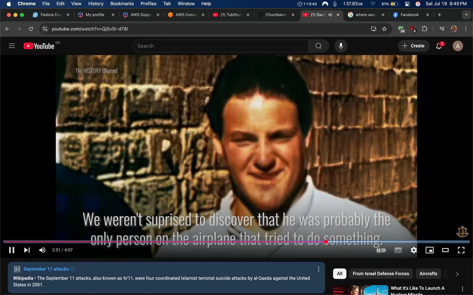 The image shows a man with dark hair and a slight smile, standing in front of a textured, possibly stone wall. He is wearing a white shirt and appears to be in a casual setting. The background is blurred, emphasizing his face. The text overlay reads, "We weren't surprised to discover that he was probably the only person on the airplane that tried to do something," suggesting a serious context related to an event, likely referencing a historical incident. 

The tone of the text implies a narrative about bravery or action in a critical situation, possibly linked to the September 11 attacks, given the context provided by the video title. The emotional weight of the statement suggests a mix of admiration and somber reflection. There are no visible logos or branding in the image itself, but the video is from The HISTORY Channel, indicating a focus on historical events. The overall composition conveys a serious tone, highlighting the gravity of the subject matter.