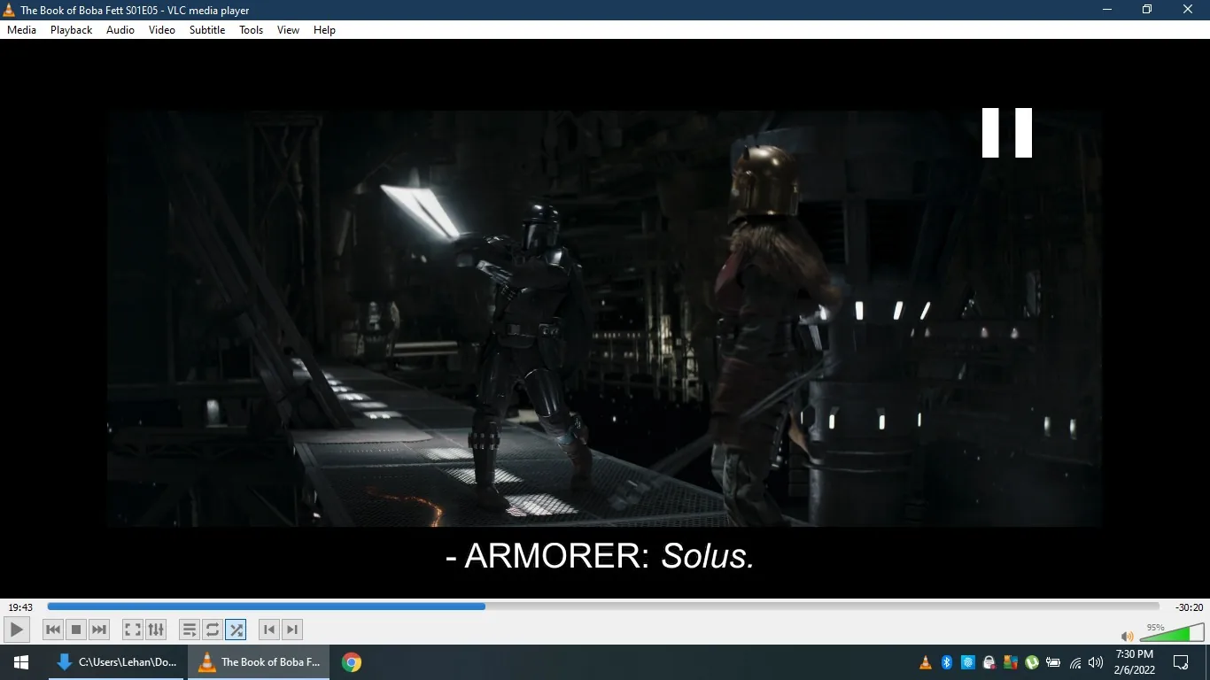 In this screenshot from "The Book of Boba Fett" Season 1, Episode 5, two characters are engaged in action. One character, known as the Armorer, is speaking, with the subtitle displaying the word "Solus." Both characters are wearing Mandalorian armor, which is distinctive for its sleek, metallic look. The foreground features a narrow walkway suspended in a dimly lit, industrial setting, suggesting a scene filled with tension and confrontation. The lighting is low, casting shadows that enhance the scene's dramatic atmosphere. The Armorer's helmet is adorned with horns, a signature element of the character's attire in the Star Wars universe. The background is filled with metallic structures and dim lights, typical of a sci-fi industrial environment. The medium is a live-action scene within a science fiction TV series, emphasizing themes of honor and combat associated with the Mandalorian culture.