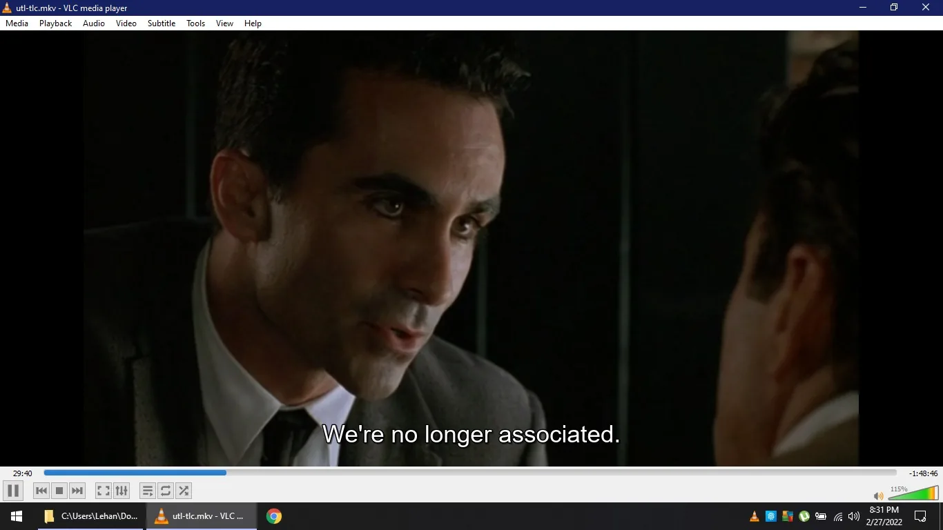 A scene from a video is displayed in VLC media player on a Windows computer. The screen shows a close-up of a man in a suit and tie, leaning slightly forward, engaged in a serious conversation. His expression is intense and focused as he speaks. The lighting is dim, suggesting a tense or dramatic moment. Subtitles at the bottom of the screen read, "We're no longer associated." The VLC media player interface is visible, showing the video file name, "utl-tlc.mkv," and the time stamp of 29:40 out of a total duration of 1:48:46. The Windows taskbar at the bottom shows various icons, including the VLC icon, indicating that it is the active application. The date and time displayed are 8:31 PM on 2/27/2022.
