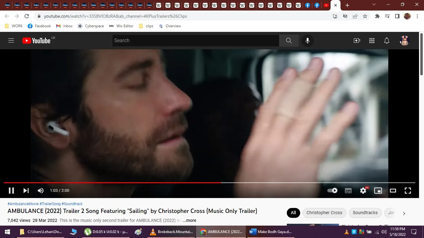 The image is a screenshot from a YouTube video titled "AMBULANCE (2022) Trailer 2 Song Featuring “Sailing” by Christopher Cross (Music Only Trailer)." It shows a close-up of a man with closed eyes, wearing wireless earbuds, seemingly lost in thought or concentrating. His hand is raised near his face, possibly in a gesture of emphasis or focus. The scene has a subdued lighting, typical of an indoor setting, giving it a dramatic and immersive feel. The man has a beard and appears to be in a vehicle, indicated by the blurred background, which suggests movement or travel. The video is from the YouTube channel "4KPlusTrailers&Clips," and the trailer is associated with the film "AMBULANCE (2022)." The image is part of a music-only trailer featuring the song "Sailing" by Christopher Cross, as indicated by the text overlay on the video. The screenshot captures a moment of introspection or intensity, typical of action or thriller film trailers.
- Title: "AMBULANCE (2022) Trailer 2 Song Featuring “Sailing” by Christopher Cross (Music Only Trailer)"
- Channel / profile: "4KPlusTrailers&Clips"
- Site / app: "YouTube"