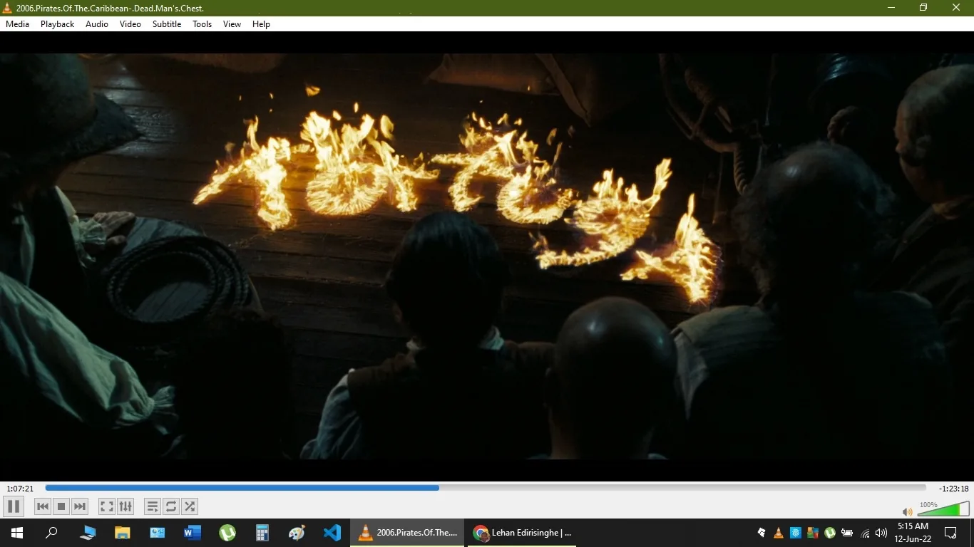```
**SECTION 2:**
The image displays a scene from the film "Pirates of the Caribbean: Dead Man's Chest." In this dramatic frame, a group of characters is seen from behind as they look at the word "Tortuga" formed in flames on a wooden surface, likely the deck of a ship. The scene is set at night, illuminated by the fiery letters, creating a warm and intense glow that contrasts with the surrounding darkness. The characters are mostly in shadow, but their silhouettes suggest they are pirates, with one wearing a hat and others having rugged attire typical of the era.
The composition focuses on the fiery text, which is central to the scene and adds an element of mystery and urgency. The lighting is dynamic, drawing attention to the word "Tortuga," a notorious pirate haven, hinting at the scene's adventurous context. The wooden planks and ropes visible around the flames add authenticity to the ship setting. The mood is tense and anticipatory, fitting the adventurous and perilous atmosphere of the film.
- Title: "2006.Pirates.Of.The.Caribbean - Dead.Man's.Chest"
- Site / app: "VLC Media Player"
- Key OCR text: "Tortuga"