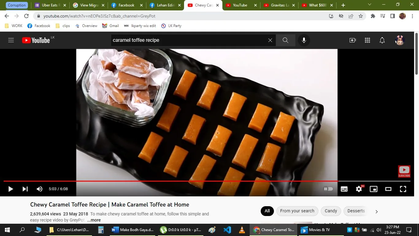 The screenshot is from a YouTube video titled "Chewy Caramel Toffee Recipe | Make Caramel Toffee at Home" on the channel GreyPot. The image shows a black tray with neatly arranged pieces of caramel toffee, each cut into rectangular shapes. The toffees have a glossy appearance, suggesting they are freshly made. To the left of the tray, there is a glass container filled with additional toffees wrapped in white paper, indicating a homemade or gift-like presentation. The background is a clean, white surface, allowing the vibrant orange-brown color of the toffees to stand out. The video seems to focus on a cooking tutorial, guiding viewers on how to make these chewy caramel toffees at home. The presence of various browser tabs at the top suggests this is a screenshot taken from a computer. The interface shows typical YouTube elements like the play button, video progress bar, and a subscribe button for the channel.