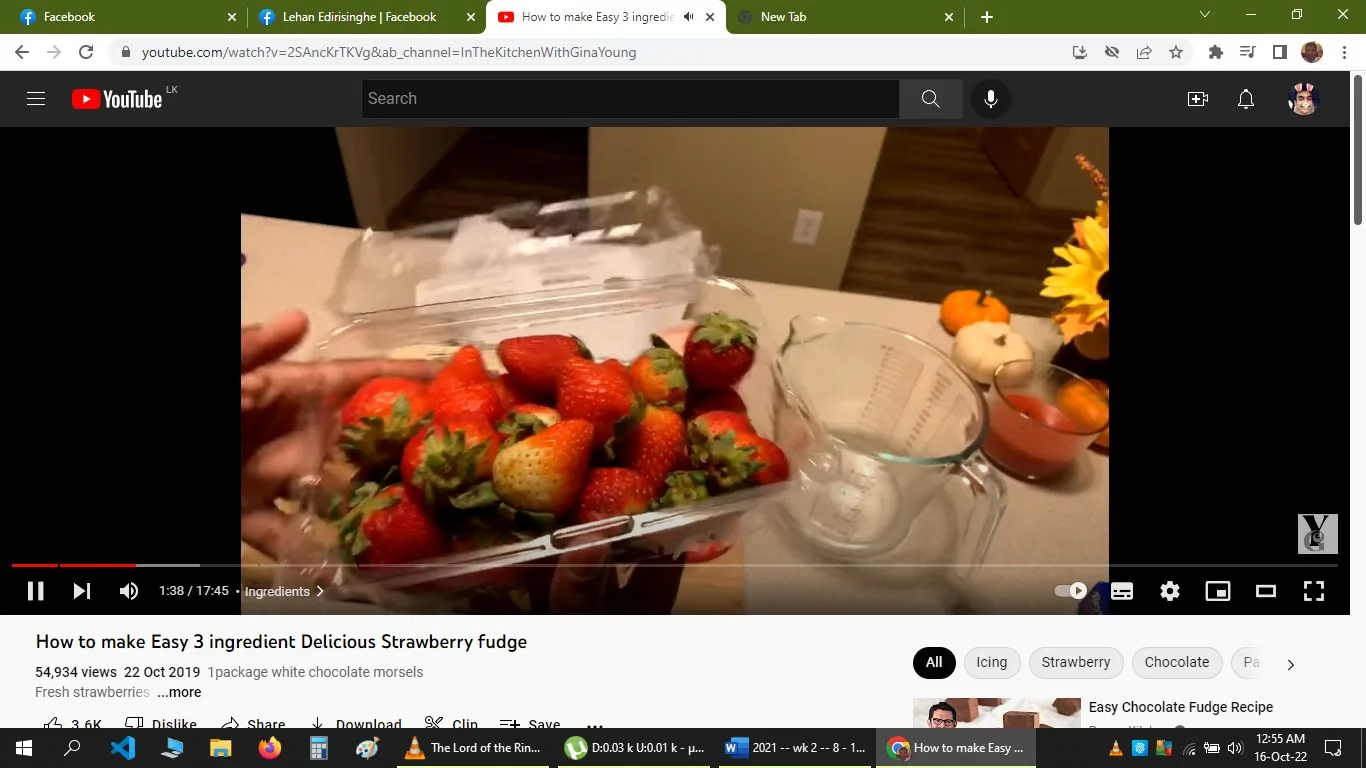The image is a screenshot from a YouTube video titled "How to make Easy 3 ingredient Delicious Strawberry fudge," hosted on the channel "InTheKitchenWithGinaYoung." The frame shows a kitchen countertop with a clear plastic container of fresh strawberries being held in the foreground. Behind the strawberries is a glass measuring cup, suggesting a cooking or baking setup. The kitchen setting is warm and inviting, with a soft, ambient light highlighting the vibrant red of the strawberries.
In the background, there are decorative elements such as a vase with sunflowers and some small pumpkins, indicating a seasonal or festive theme. The video likely provides a cooking tutorial, focusing on making strawberry fudge with minimal ingredients, as suggested by the title and the presence of strawberries. The image captures a moment early in the preparation process, emphasizing the freshness and quality of the ingredients used.
- Title: "How to make Easy 3 ingredient Delicious Strawberry fudge"
- Channel / profile: "InTheKitchenWithGinaYoung"
- Site / app: "YouTube"