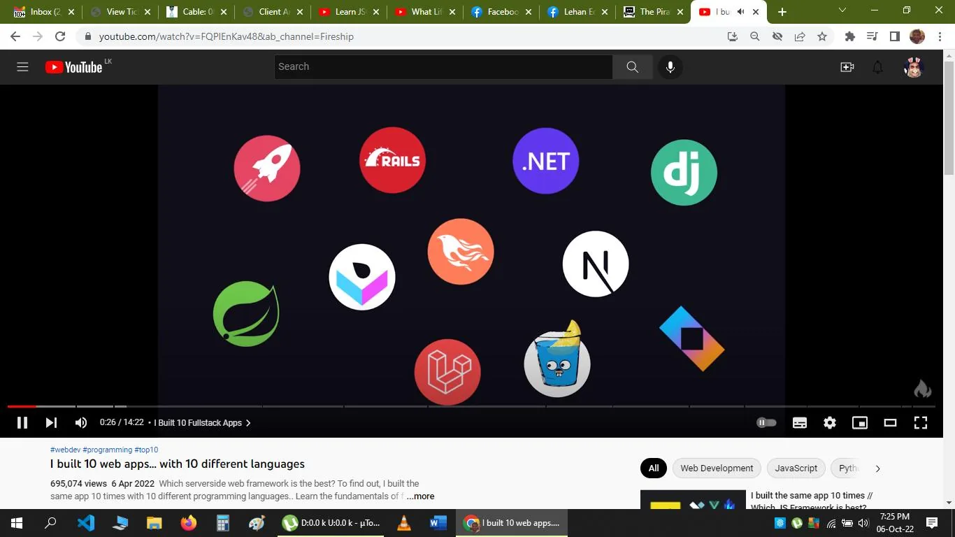 The screenshot displays a YouTube video titled "I built 10 web apps... with 10 different languages" from the channel Fireship. It's part of a video exploring which server-side web framework is the best by building the same app using ten different programming languages. The video was published on April 6, 2022, and has 695,074 views.
In the image, various programming framework logos are arranged in a grid-like pattern against a dark background. These include recognizable symbols such as the Rails logo, the .NET symbol, and others representing popular frameworks like Django, Spring, and Laravel. Each logo is distinct and colorful, creating a vibrant visual contrast against the dark background. The YouTube interface is visible, showing the video play bar, view count, and the video description with tags like "web development," "JavaScript," and "Python." The scene captures the essence of popular web development tools, indicating a comprehensive tutorial or comparison video.