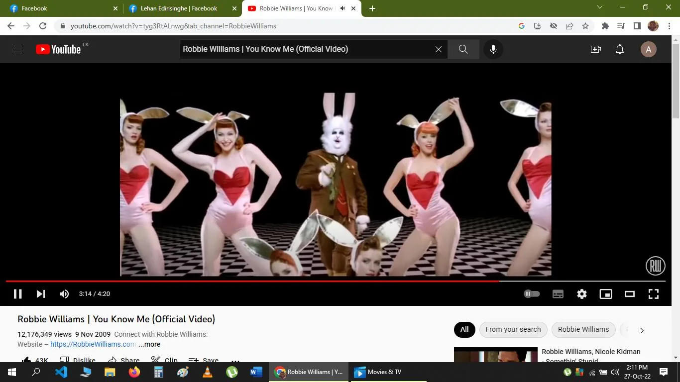 Robbie Williams' music video for "You Know Me" features a whimsical and theatrical scene. In the center stands a character dressed as a white rabbit, complete with large ears and holding a carrot, evoking a fantasy or Alice in Wonderland theme. Surrounding the rabbit are several dancers dressed in retro-style costumes, featuring pink bodysuits with red heart designs and bunny ears, adding to the surreal and playful atmosphere. The backdrop consists of a checkered floor pattern, enhancing the dreamlike quality of the scene. The lighting is bright and colorful, matching the upbeat and lively mood of the music video. The dancers strike synchronized poses, suggesting a choreographed performance. The style is visually striking and imaginative, fitting the eccentric and creative nature of Robbie Williams' music and persona. The video is set in a controlled studio environment, focusing on fantasy elements and theatrical performance.
- Title: "Robbie Williams | You Know Me (Official Video)"
- Channel / profile: "RobbieWilliams"
- Site / app: "YouTube"