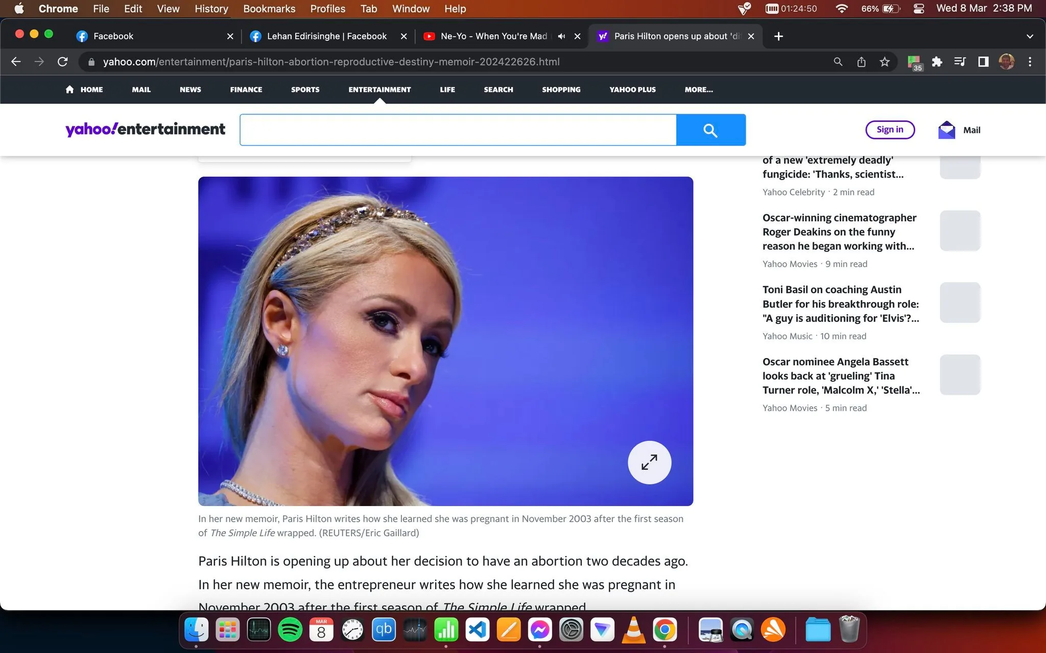 The image is a screenshot from Yahoo Entertainment, featuring an article about Paris Hilton. The headline reads, "Paris Hilton opens up about 'difficult' decision to have an abortion," indicating a personal story shared by the celebrity. The screenshot includes a portrait of Paris Hilton, who is known for her iconic style and presence. She is shown in a close-up shot, against a blurred blue background that adds a serene yet serious tone to the image. Paris Hilton is wearing a headband adorned with jewels, matching earrings, and a necklace that complements her outfit. Her expression appears contemplative, fitting the serious nature of the article. Text on the screen mentions that in her new memoir, Paris Hilton discusses her experience with pregnancy after the first season of "The Simple Life" wrapped in 2003. The page layout suggests a digital interface with navigation tabs at the top, typical of an online publication. The article is published by Yahoo, and the image credits include REUTERS/Eric Gaillard.