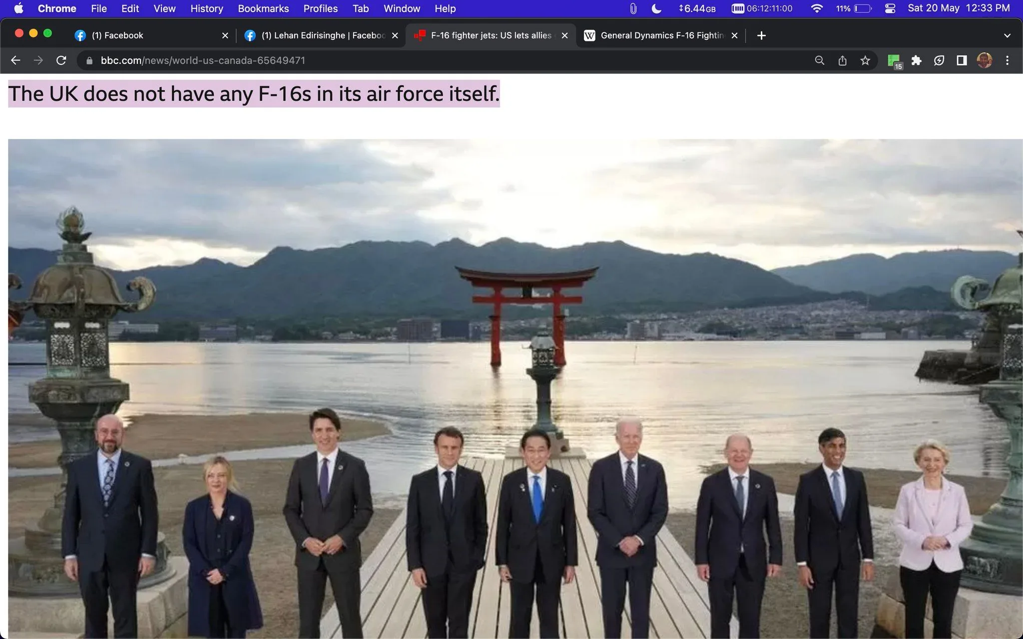 The screenshot displays an article on the BBC website. The title reads, "The UK does not have any F-16s in its air force itself." Below this headline is an image of a group of individuals standing in an outdoor setting against a picturesque backdrop. The people are aligned in a straight line on a wooden platform by the water, with a traditional torii gate and mountainous landscape visible in the background. The photograph appears to be taken at a famous scenic location, likely in Japan, given the torii gate. The individuals are dressed formally, wearing suits and formal attire, suggesting a diplomatic or official event. The mood is formal yet relaxed, with everyone standing in a composed manner. The lighting is natural, indicating it is either early morning or late afternoon. The scene suggests a meeting of international importance, possibly a summit or conference.