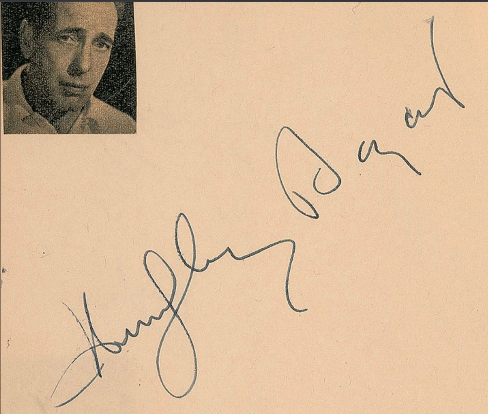 The image features an autograph of Humphrey Bogart, prominently displayed across the right side of the image. The signature is written in a bold, cursive style, with large, sweeping letters that are characteristic of traditional autographs. In the upper left corner, there is a small, black-and-white photograph of Humphrey Bogart, showing him with a thoughtful expression. The photograph captures only his face and upper shoulders, giving a close-up view that emphasizes his features. The background is a plain, light beige, which helps to highlight both the photograph and the signature. The overall composition is simple but elegant, focusing on the notable signature and the accompanying portrait of the famous actor. There are no additional texts or branding visible, keeping the attention on the autographed name.