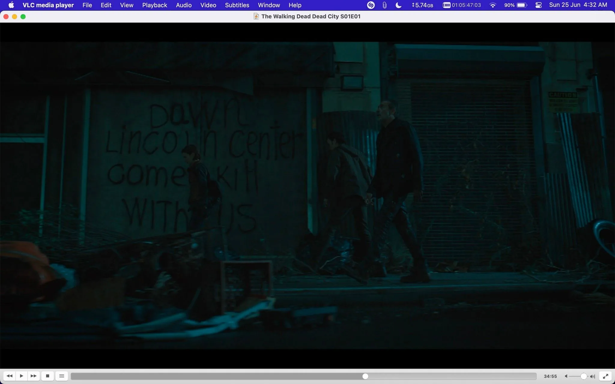 The screenshot is from a scene in "The Walking Dead Dead City S01E01," displayed in VLC media player. It depicts a dark, urban setting at night, with three figures walking along a dimly lit street. The atmosphere is tense and gritty, typical of a post-apocalyptic environment. The characters are dressed in dark, practical clothing, suitable for survival in a dangerous world.
In the foreground, there is debris and a clutter of objects, suggesting neglect and abandonment. The background features a building with graffiti that reads, "Dawn Lincoln Center come kill with us," adding to the ominous mood. The lighting is minimal, casting shadows and enhancing the scene's mysterious and foreboding tone. The overall composition suggests a moment of tense anticipation or exploration in the storyline. The muted colors and urban decay emphasize the themes of survival and the harsh realities faced by the characters.
