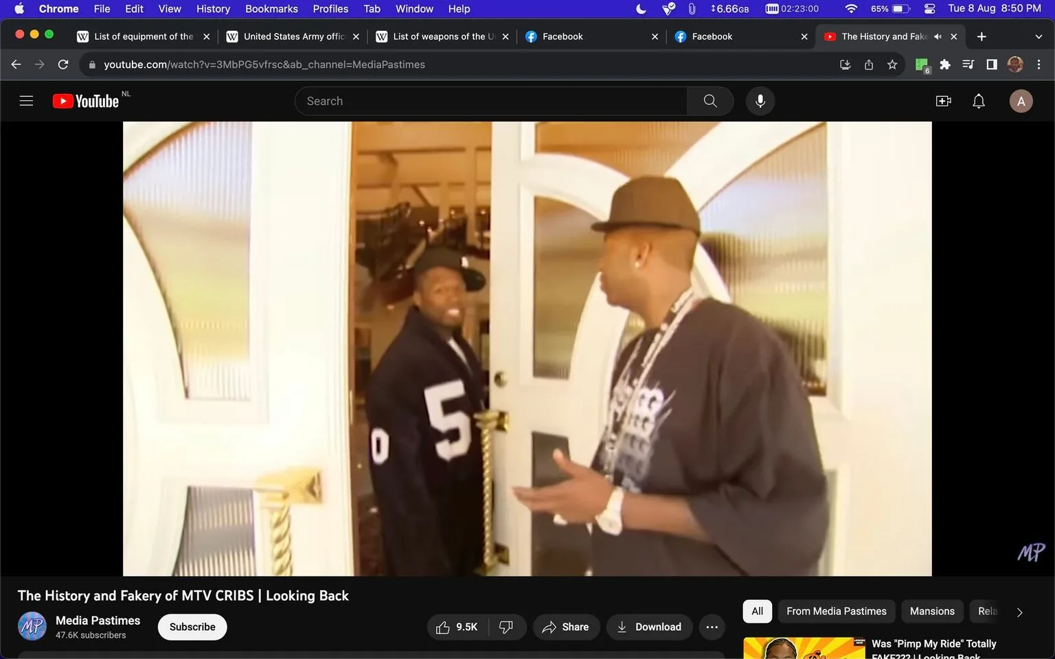 The image is a frame from a YouTube video titled "The History and Fakery of MTV CRIBS | Looking Back," featured on the channel Media Pastimes. The scene captures a casual interaction between two individuals at a doorway. The man on the left, identified as 50 Cent, is standing at the threshold, holding the door open and smiling. He is wearing a black jersey with the number "5" prominently displayed, and his cap is tilted to the side, adding a relaxed vibe to his appearance.
The individual on the right, whose back is facing the camera, is engaged in conversation with 50 Cent. He is wearing a dark sweater adorned with a graphic print, a large chain, and a hat. The setting is indoors, with the doorway leading into what seems to be a spacious and well-lit interior, possibly a luxurious home—a fitting backdrop for a show like "MTV CRIBS," known for showcasing celebrity homes. The lighting is warm, enhancing the welcoming atmosphere of the scene. The video frame is part of a retrospective analysis of the show, exploring its history and elements of "fakery" associated with it.
- Title: "The History and Fakery of MTV CRIBS | Looking Back"
- Channel / profile: "Media Pastimes"
- Site / app: "YouTube"