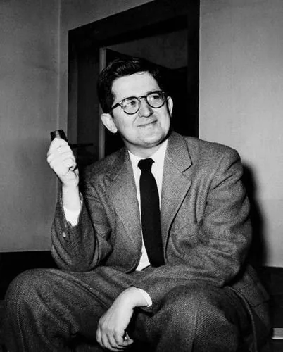 AM Rosenthal, a notable figure in journalism, is captured in this black-and-white photograph. He is seated indoors, wearing a suit with a subtle checkered pattern, paired with a white shirt and a dark tie. Rosenthal holds a pipe in his right hand, suggesting a moment of contemplation or relaxation, and he has a slight, thoughtful smile on his face. His hair is neatly combed, and he is wearing glasses, which contribute to his intellectual appearance. The setting appears to be a simple room with plain walls and a doorframe visible in the background, adding a sense of modesty to the scene. The lighting is straightforward, typical of mid-20th-century photography, highlighting his features clearly. The image reflects a moment in time, likely from the 1950s, illustrating Rosenthal as a confident and thoughtful individual in his professional environment.