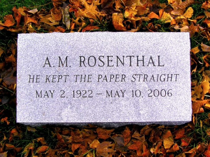 A gravestone marking the resting place of AM Rosenthal is featured prominently in this image. The stone is a polished gray granite, rectangular in shape, and set flat into the ground. It is surrounded by fallen autumn leaves in shades of brown and gold, indicating the season. The engraving on the stone reads "A. M. Rosenthal," accompanied by the phrase "He kept the paper straight," which suggests his significant contribution to journalism. Below this, the dates "May 2, 1922 - May 10, 2006" are inscribed, marking his lifespan. The setting appears to be a cemetery, providing a solemn and respectful backdrop to the scene. The lighting is natural, possibly suggesting a calm, overcast day, which adds to the reflective mood of the image.